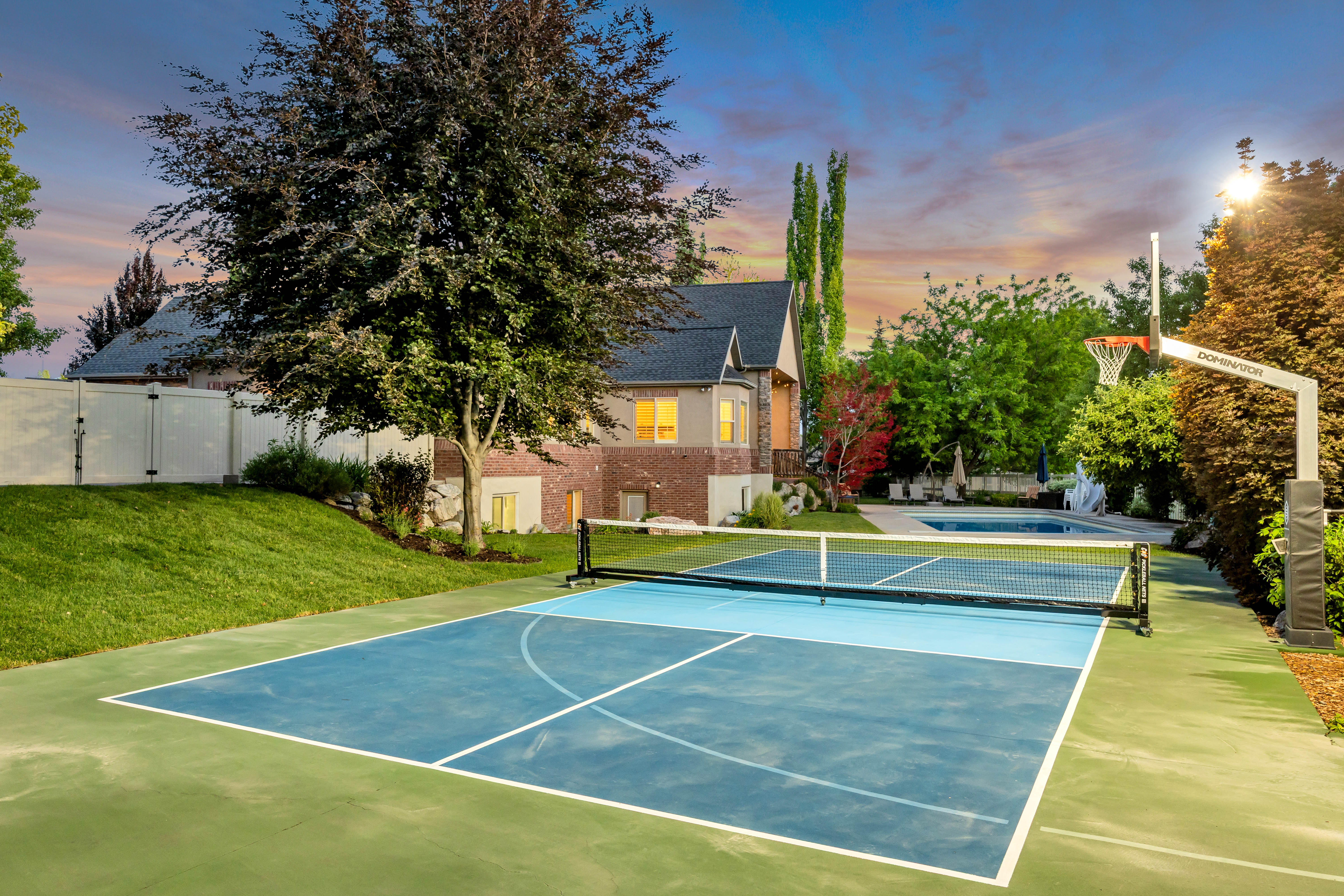 Multi-sport court with pickleball lines, basketball hoop, and adjacent swimming pool