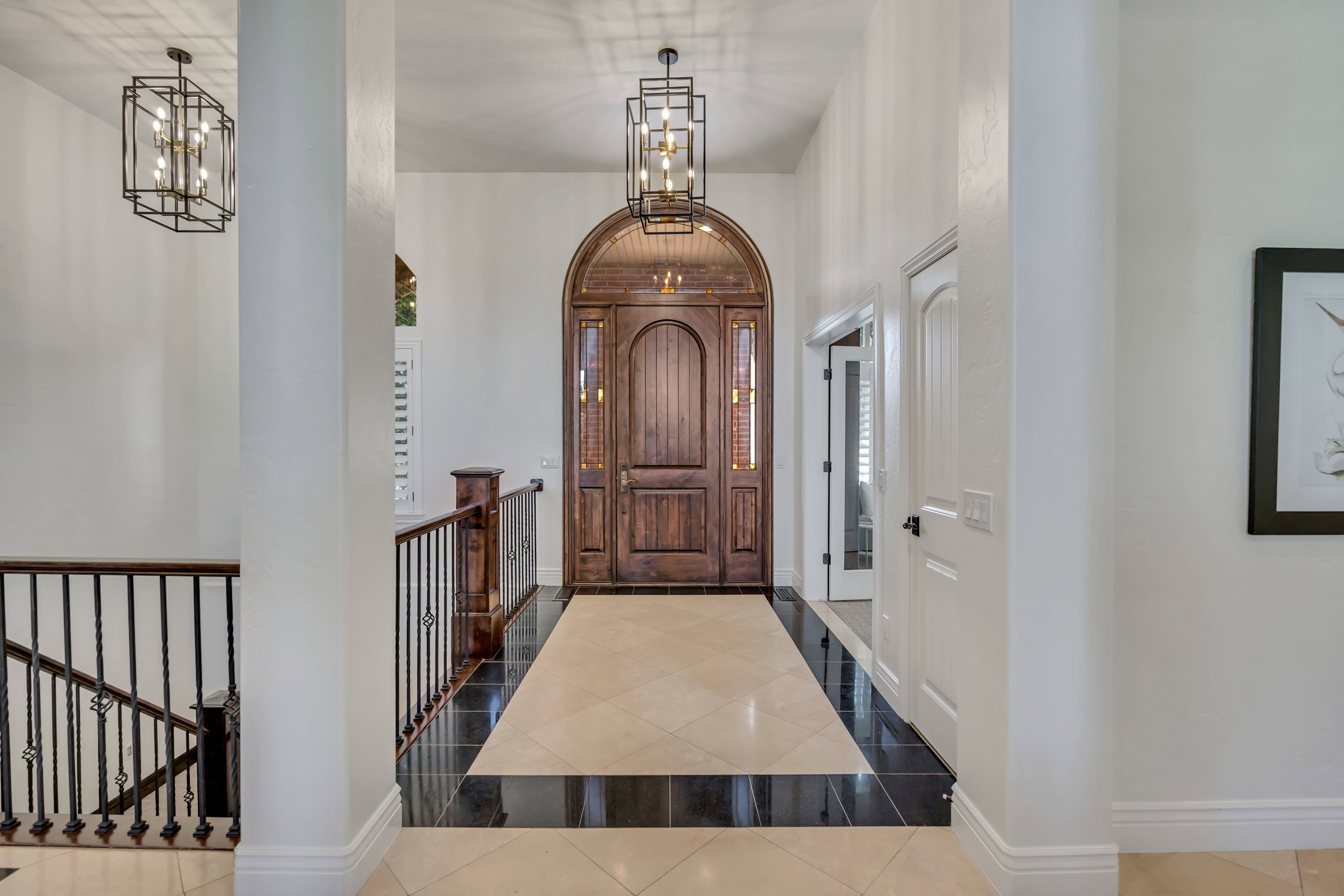 Double-door arched entry featuring decorative glass inserts and rich wood tones