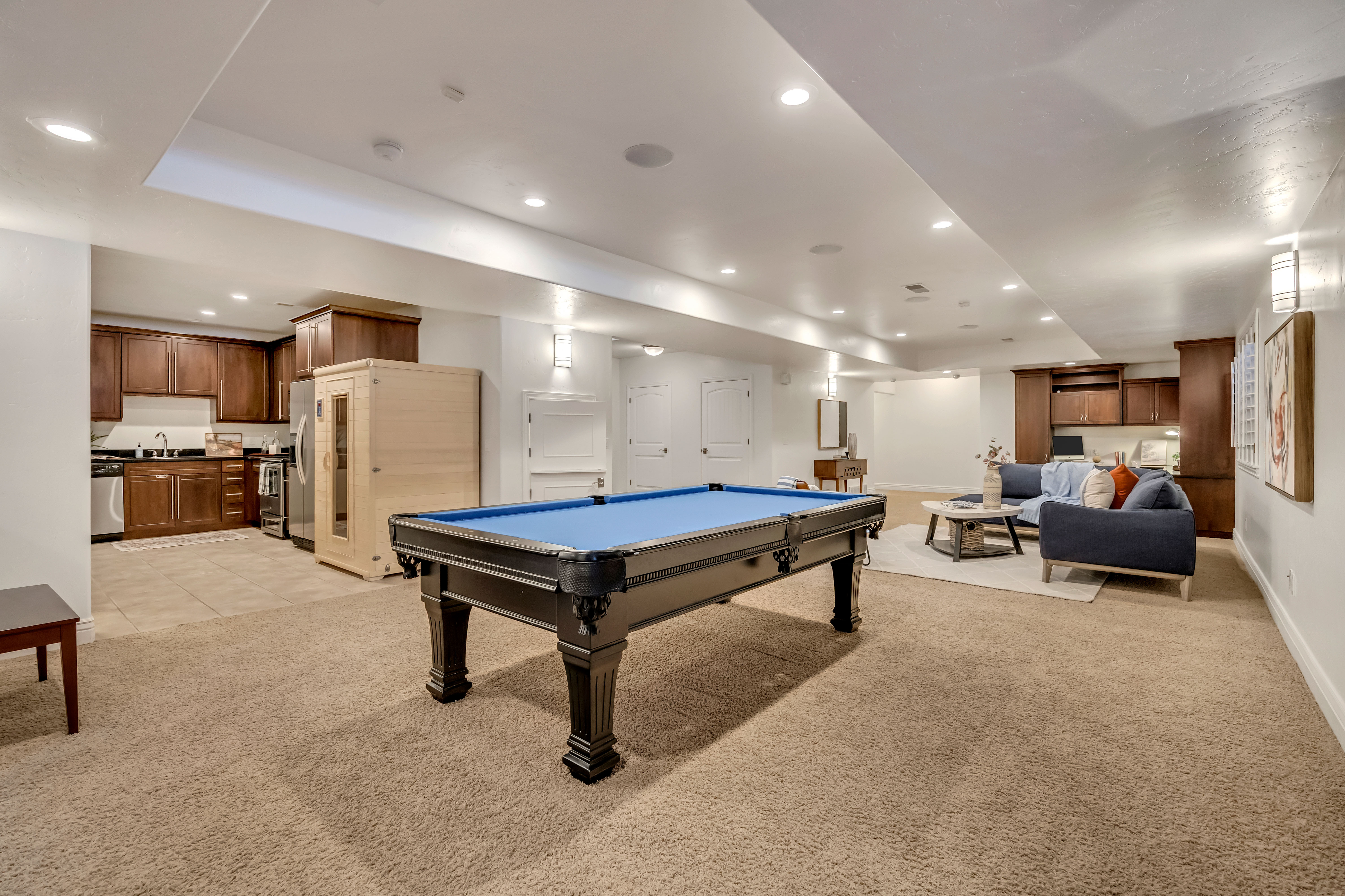 Open-concept lower level featuring recessed lighting, plush carpeting, and a full secondary kitchen with cabinetry and appliances