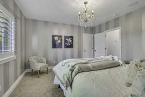 Bedroom featuring striped accent walls, plush carpet flooring, a crystal chandelier, and shuttered windows