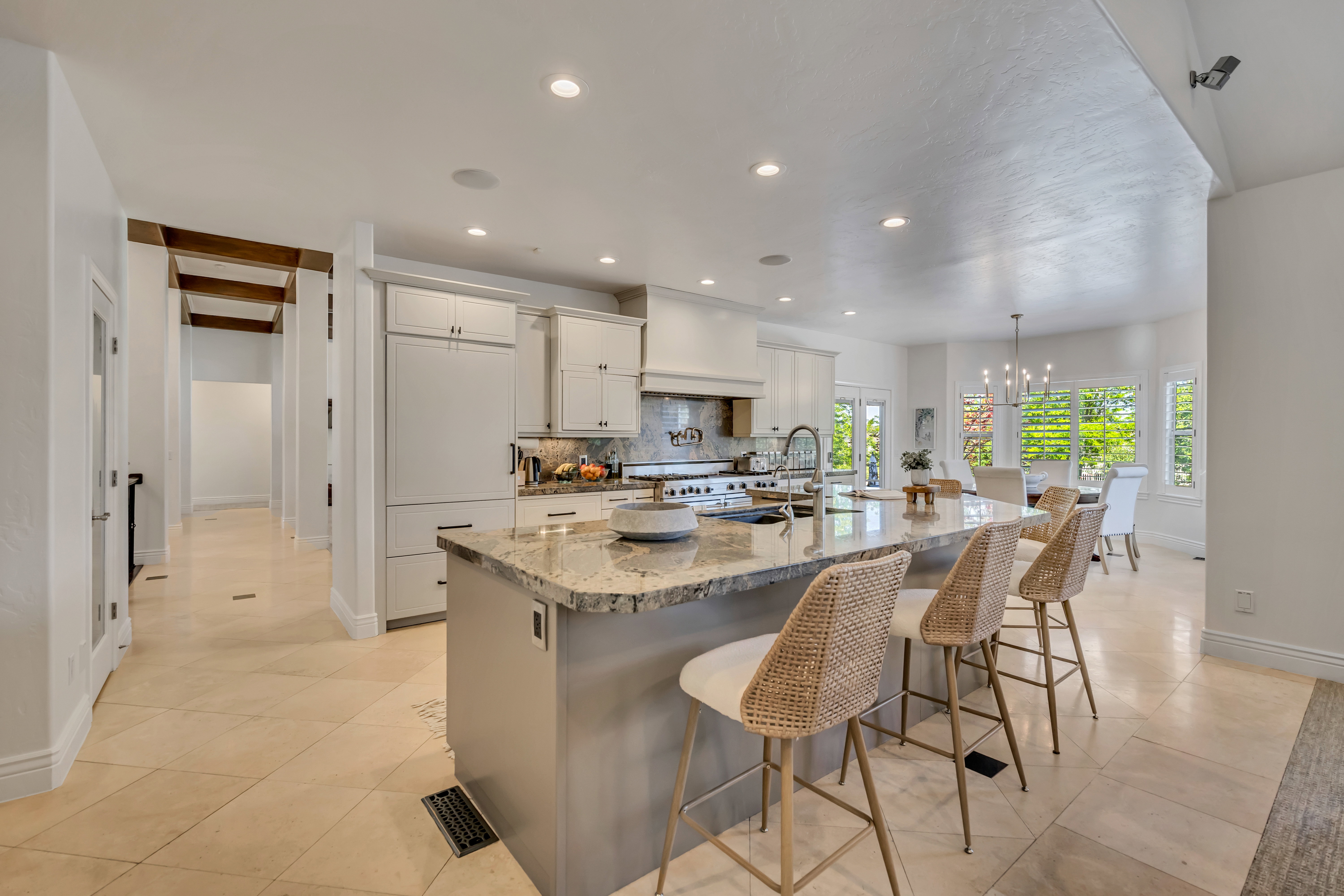 Gourmet kitchen with a large island featuring a stone countertop, white cabinetry, and stainless steel appliances