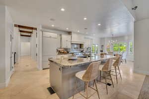 Gourmet kitchen with a large island featuring a stone countertop, white cabinetry, and stainless steel appliances