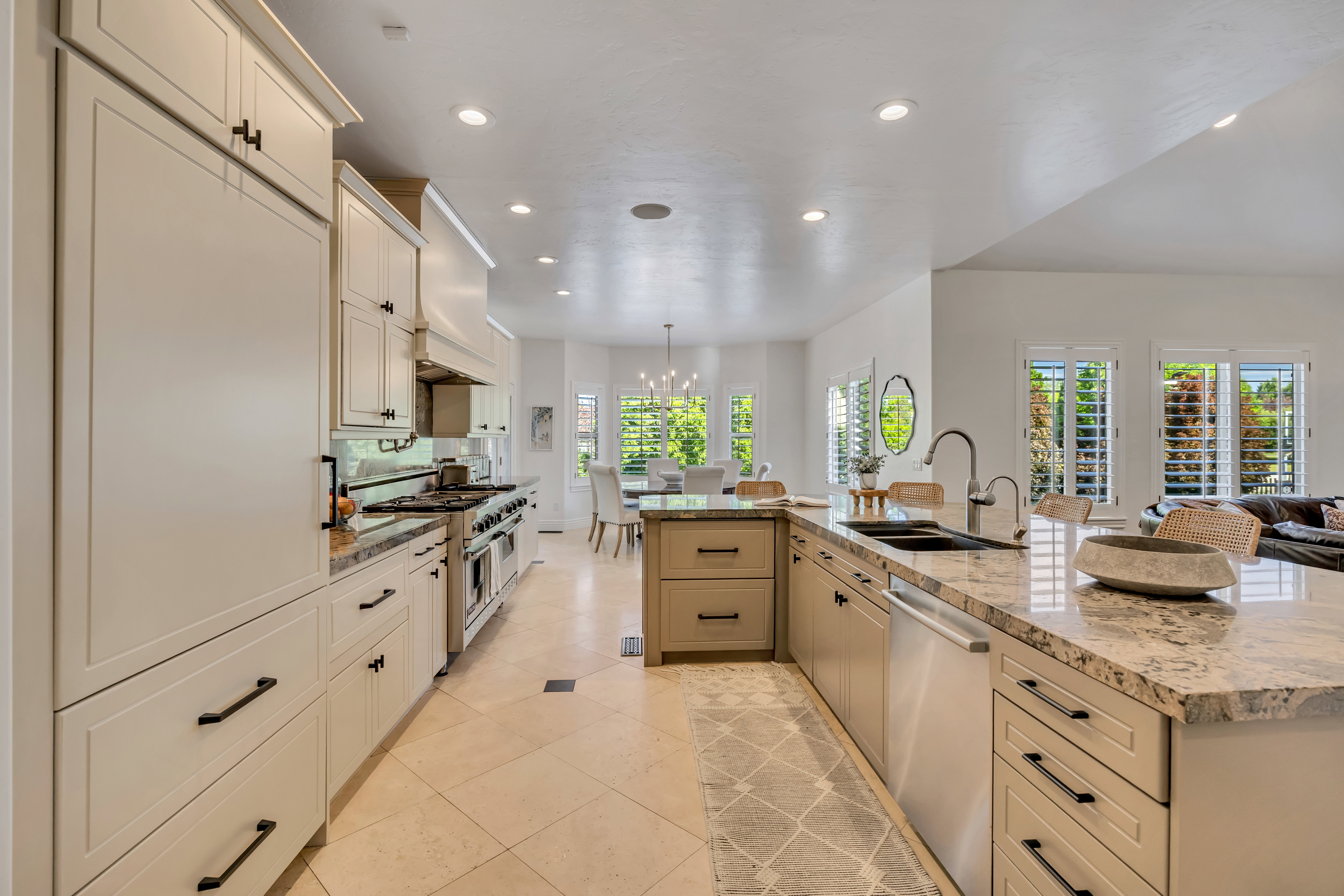 Gourmet kitchen featuring a large island with sink, stainless steel appliances, extensive cabinetry, stone countertops, and recessed lighting