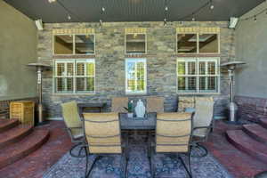 Covered patio featuring a stone veneer wall, shuttered windows, and a ceiling with integrated lighting
