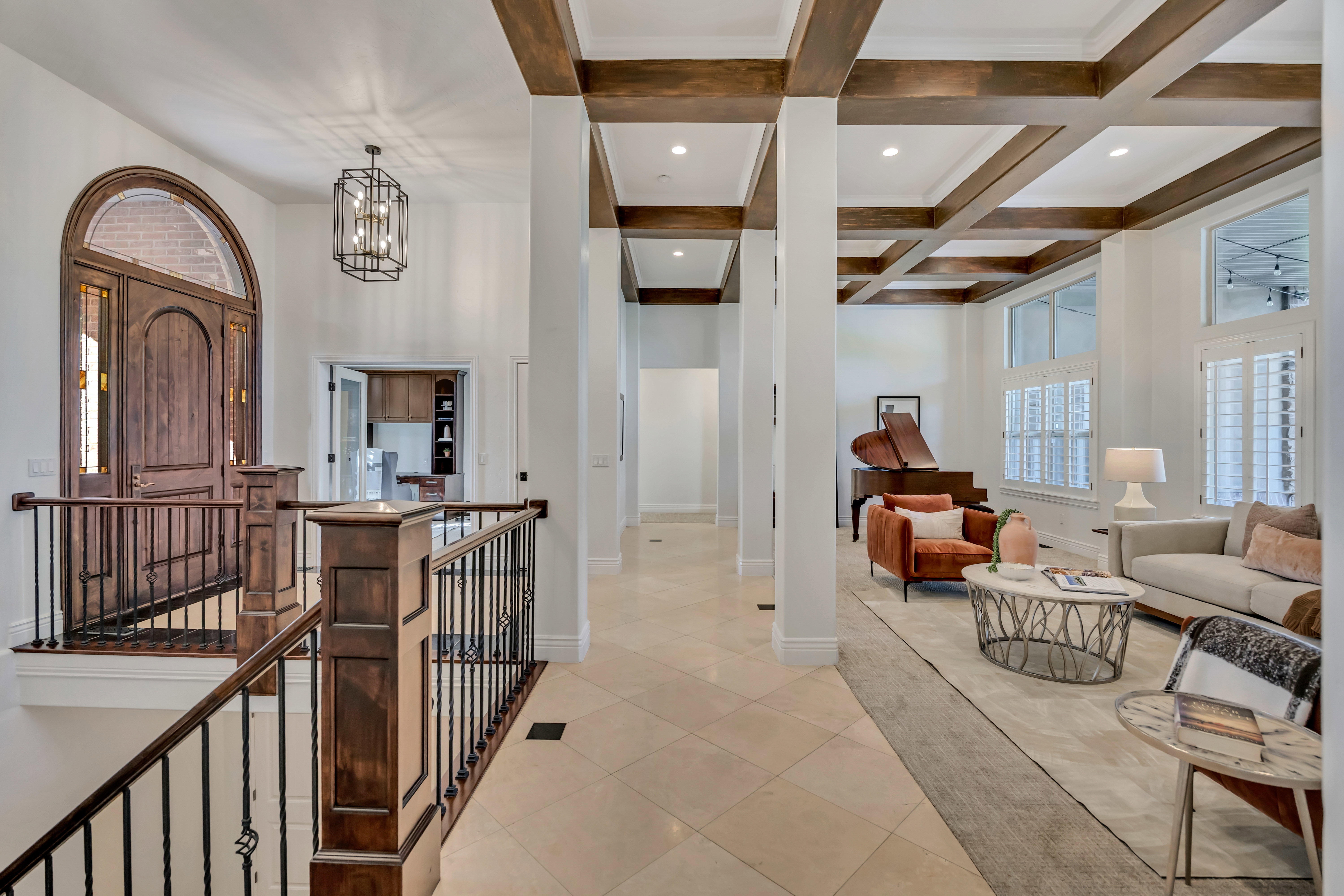 Grand entry foyer with an arched wooden door and wrought iron banister