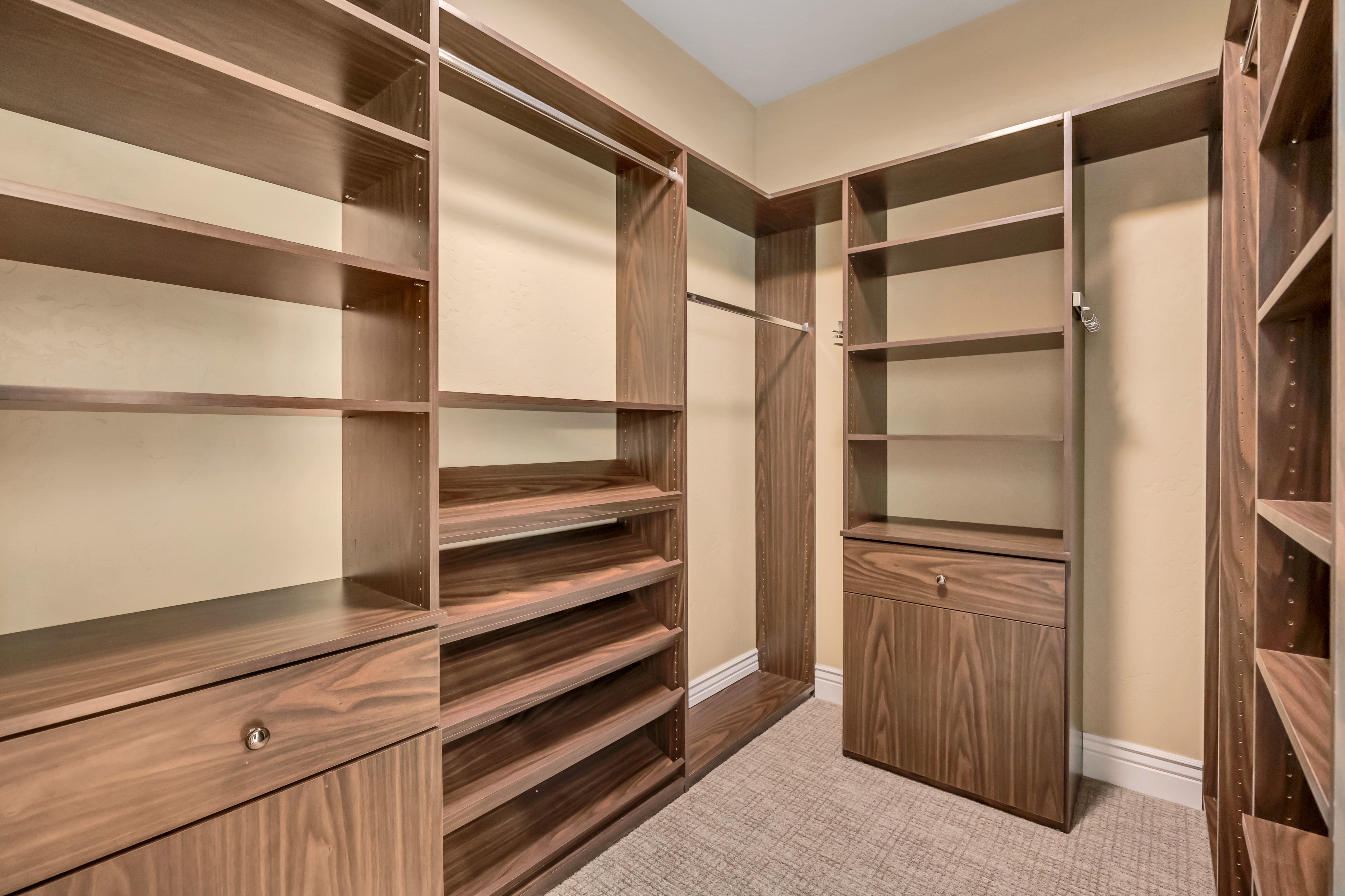 Built-in closet system featuring wood-finish shelving, multiple hanging rods, and integrated drawers with polished hardware