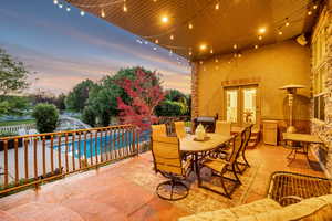 Covered patio with string lighting, direct access to the interior via French doors, and a stone-clad exterior wall