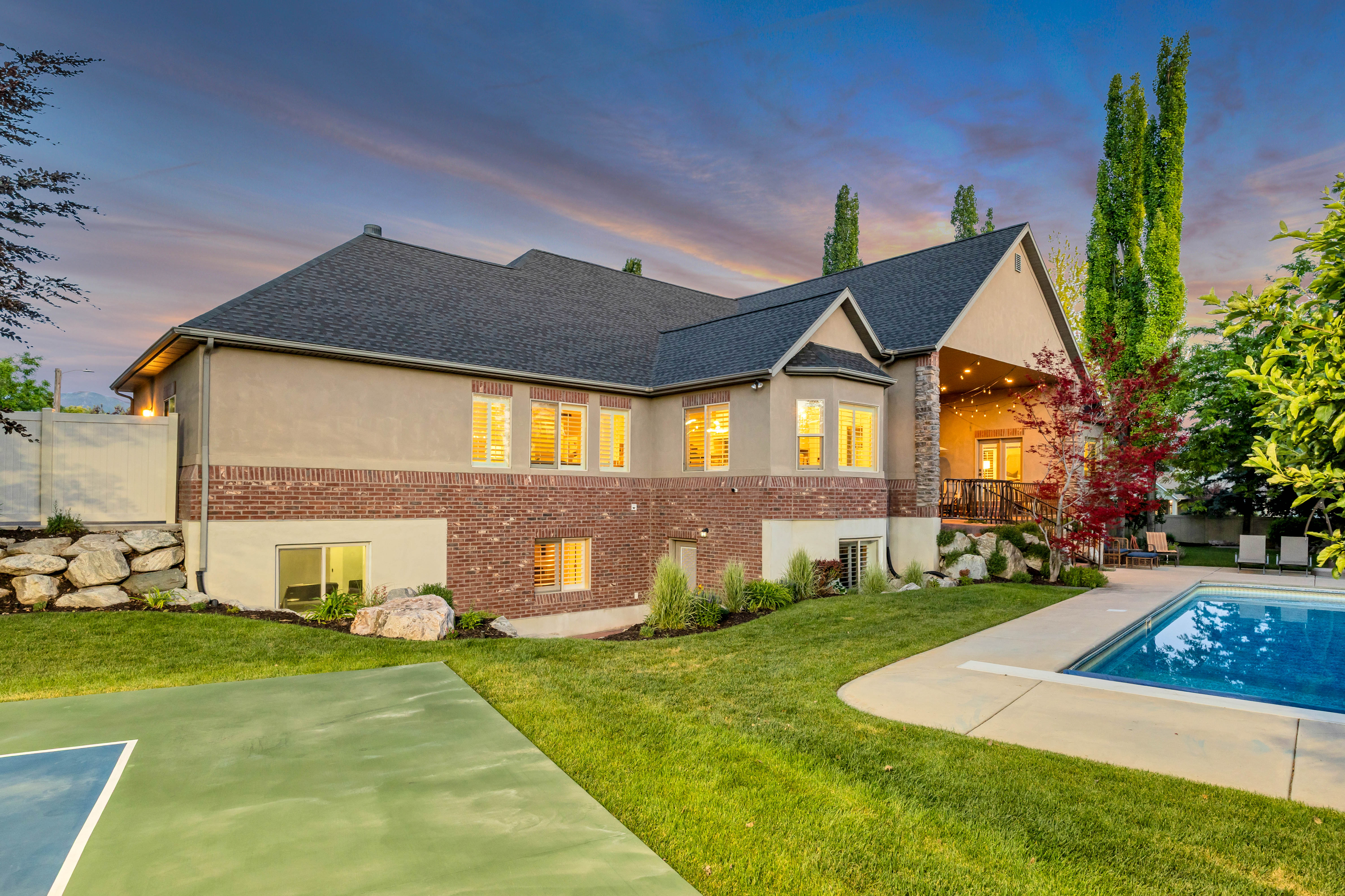 Expansive backyard featuring a rectangular swimming pool, concrete patio, and a painted sports court