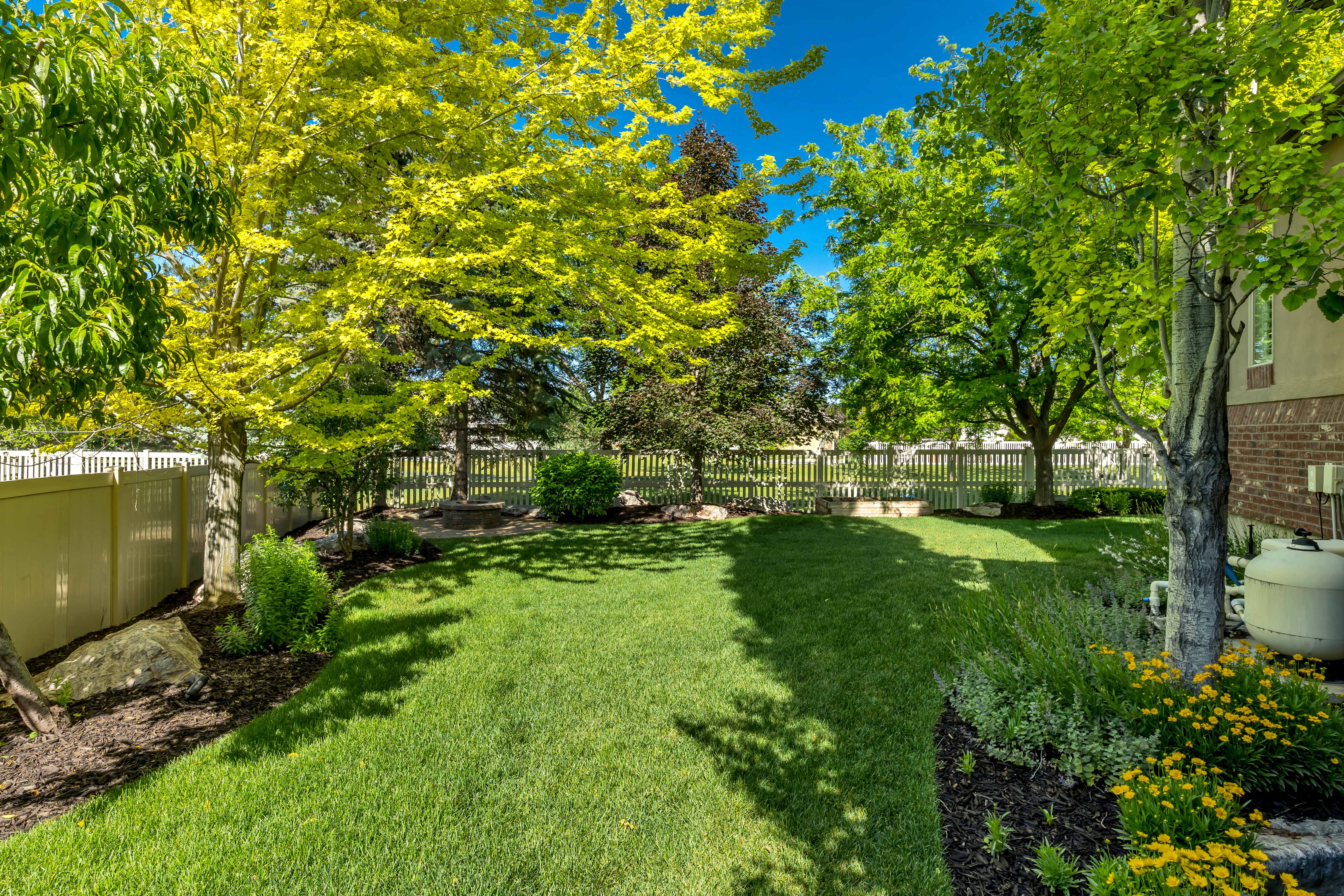 Expansive backyard featuring a lush lawn, mature trees, and established perimeter landscaping