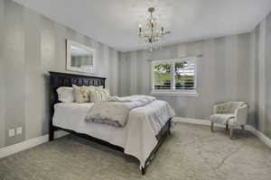 Bedroom featuring striped wall treatment, ceiling-mounted chandelier, and window with plantation shutters
