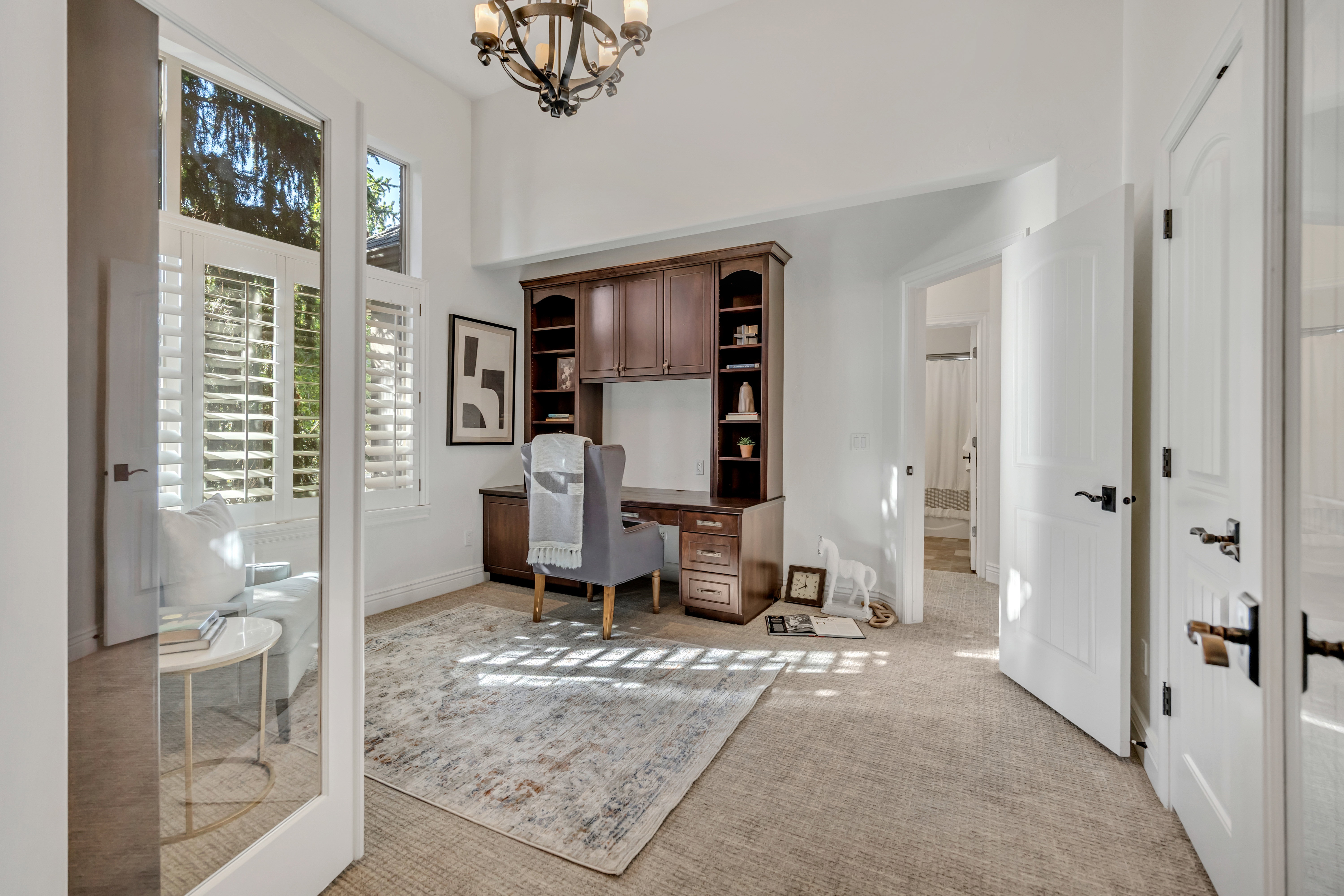 Dedicated office space featuring built-in wood cabinetry with shelving, high ceilings, and an ornate chandelier