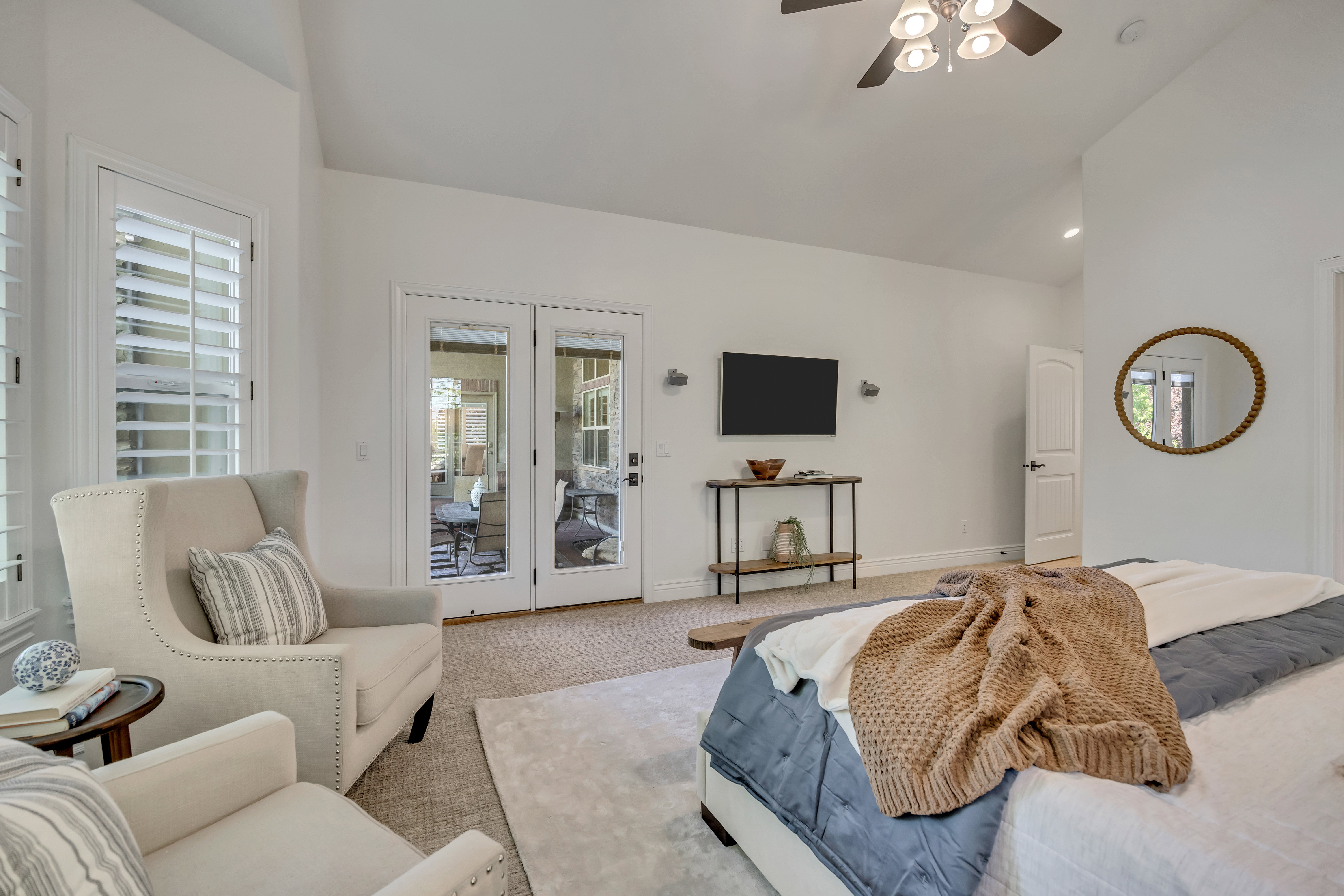 Carpeted room featuring white plantation shutters, French doors, a ceiling fan with integrated lighting, and vaulted ceilings