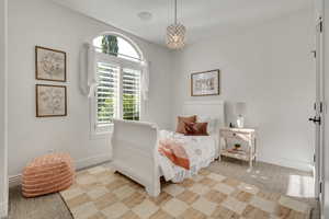 Bright room featuring an arched window with plantation shutters, a decorative chandelier, and light-toned walls