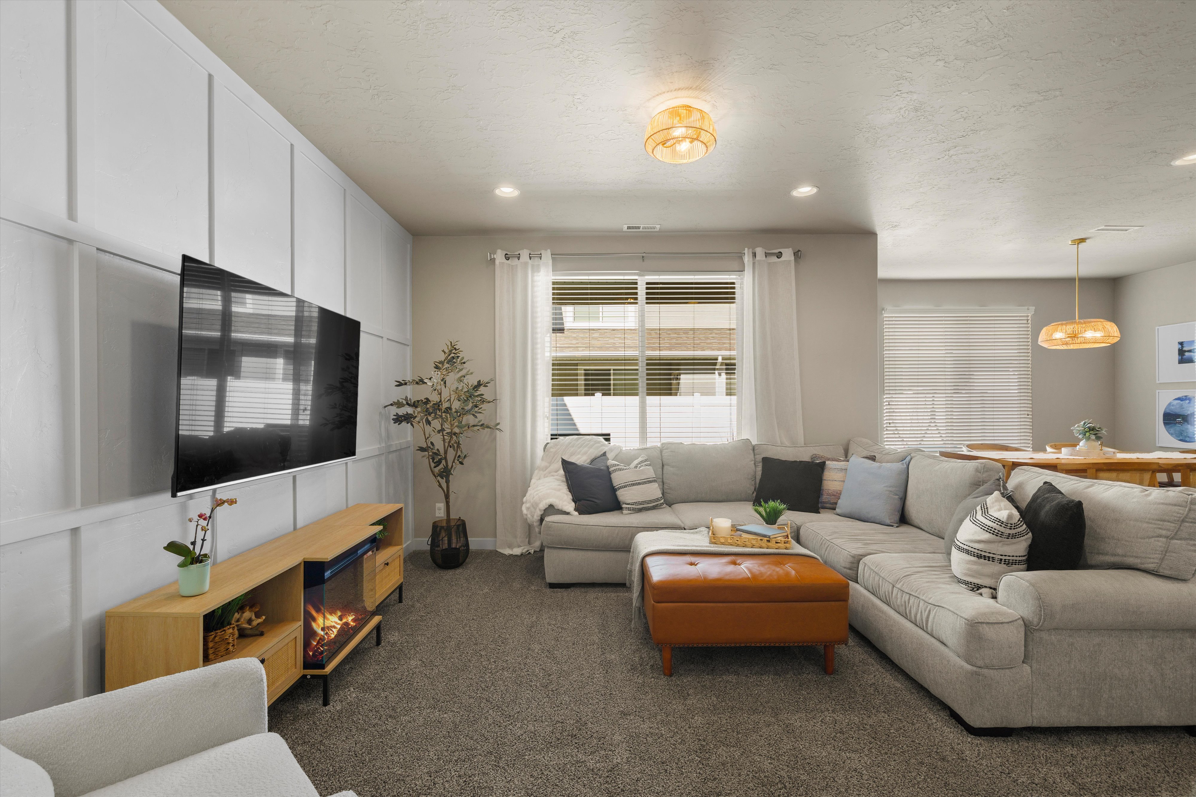 Open-concept living area featuring a prominent board-and-batten accent wall, recessed lighting, and a modern ceiling fixture