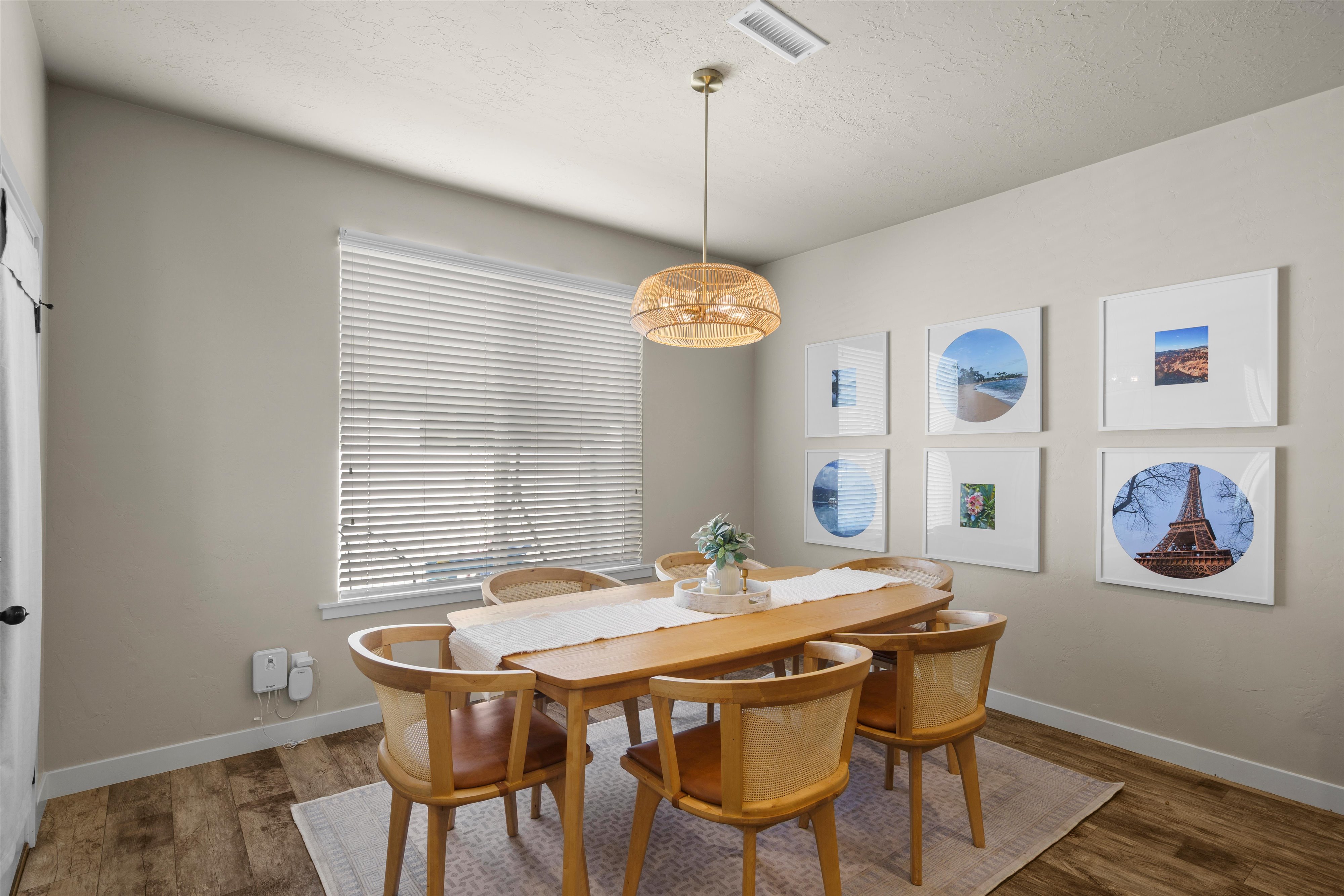 Dining area featuring wood-finish flooring, a contemporary ceiling light fixture, a window with blinds, and light-toned wall paint