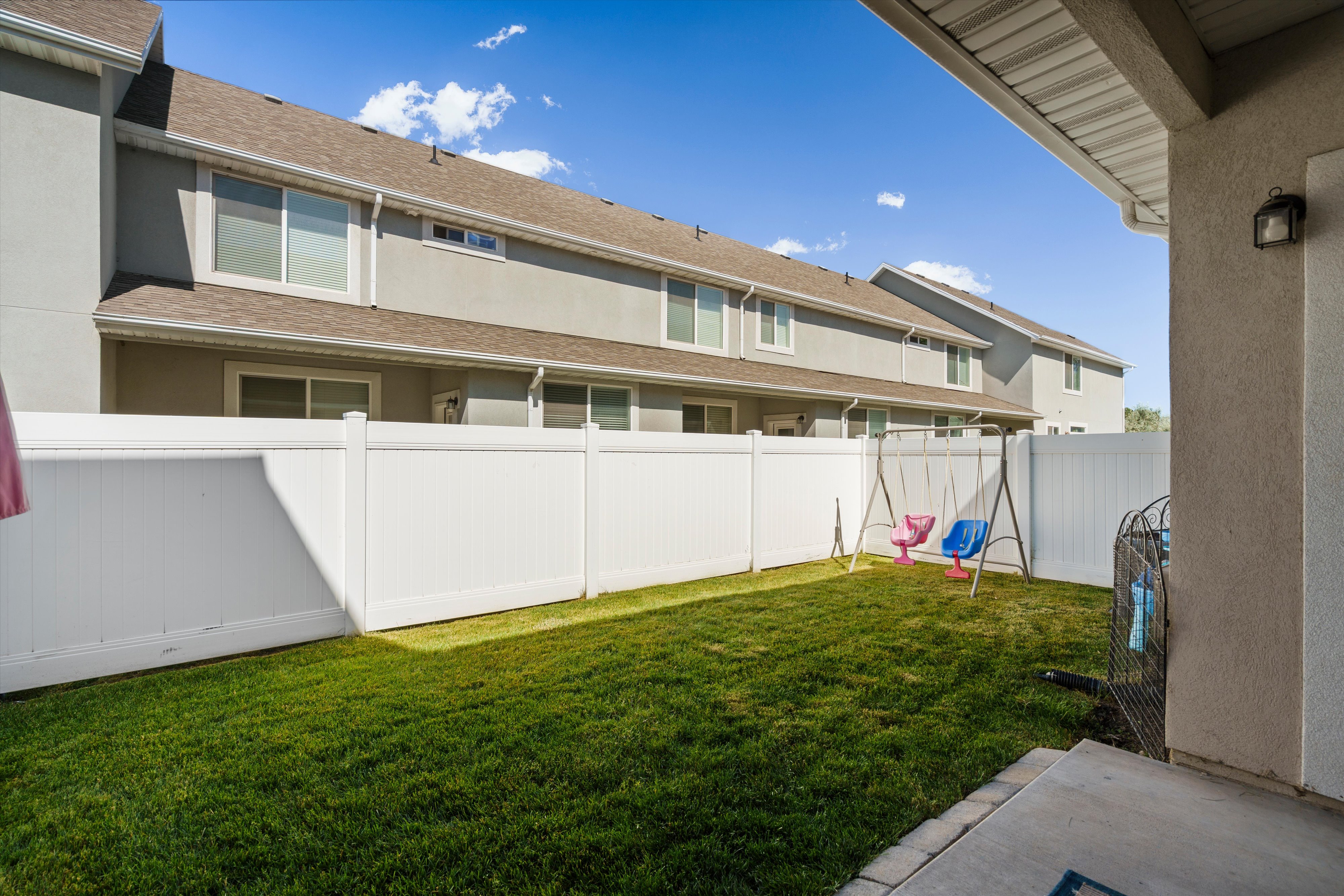Private fenced backyard featuring a manicured lawn, concrete patio, and exterior lighting fixture