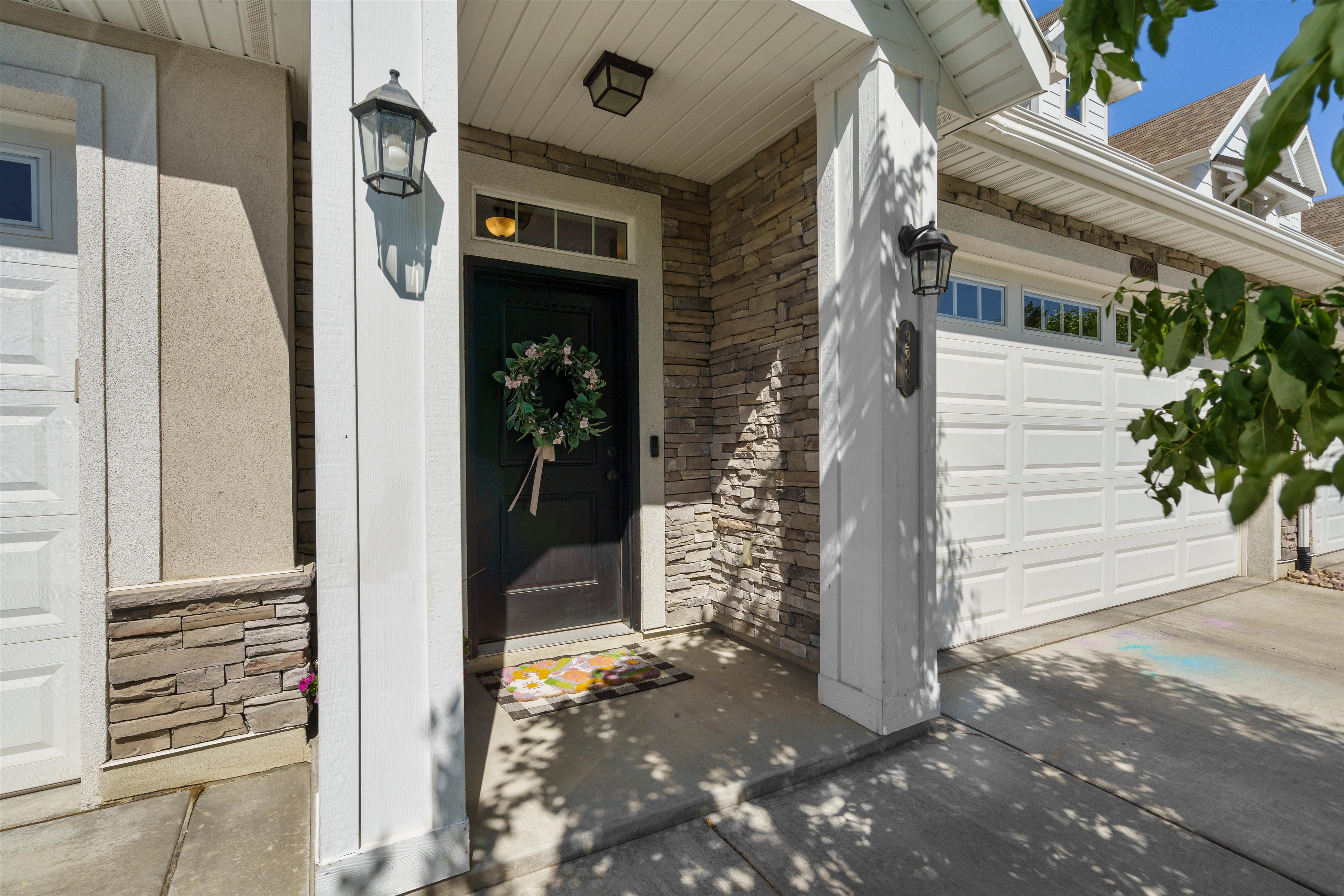 Entryway featuring a dark paneled door with transom window, stone veneer accents, white paneling, and an overhead light fixture