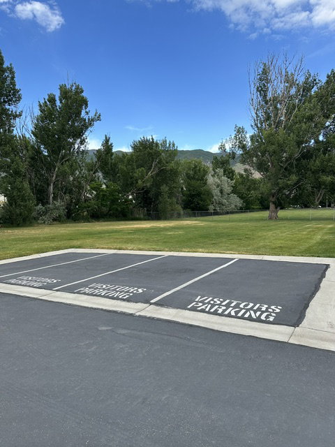 Paved visitor parking area with clearly marked spaces, bordered by a concrete curb