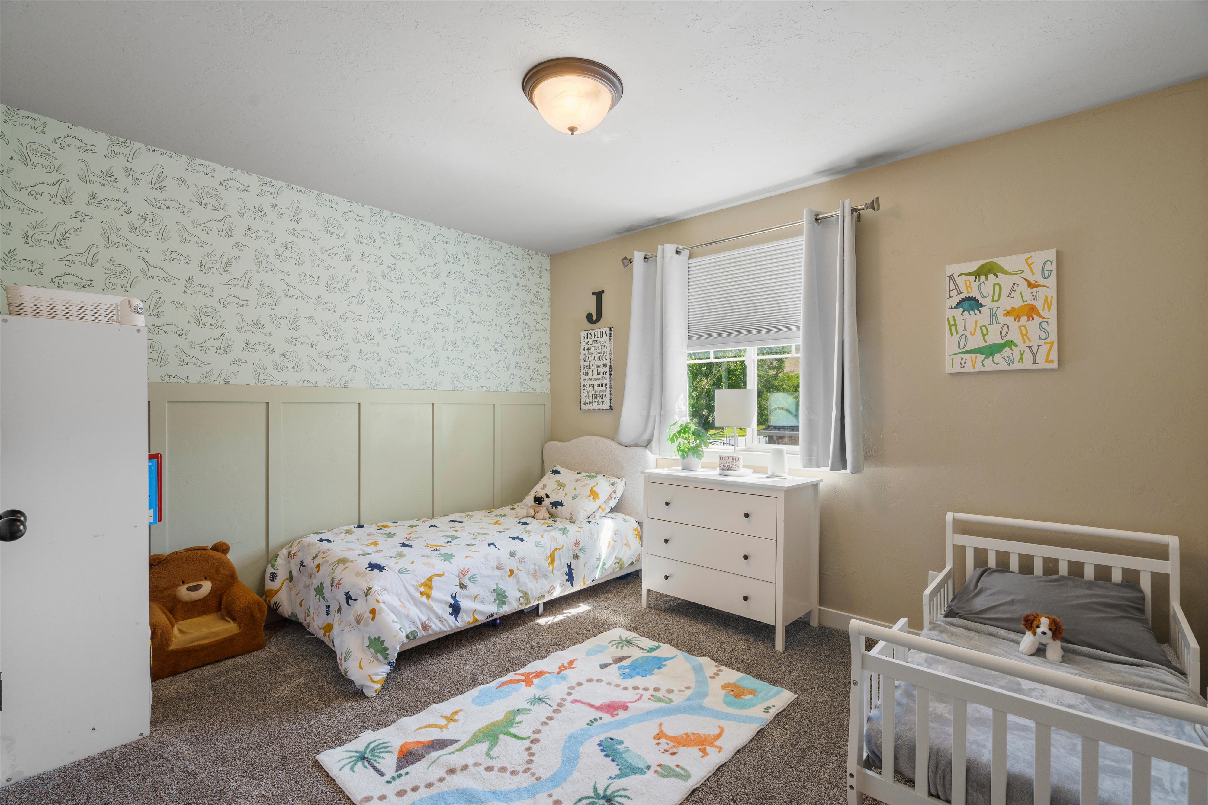 Bedroom featuring light-colored walls and a patterned accent wall
