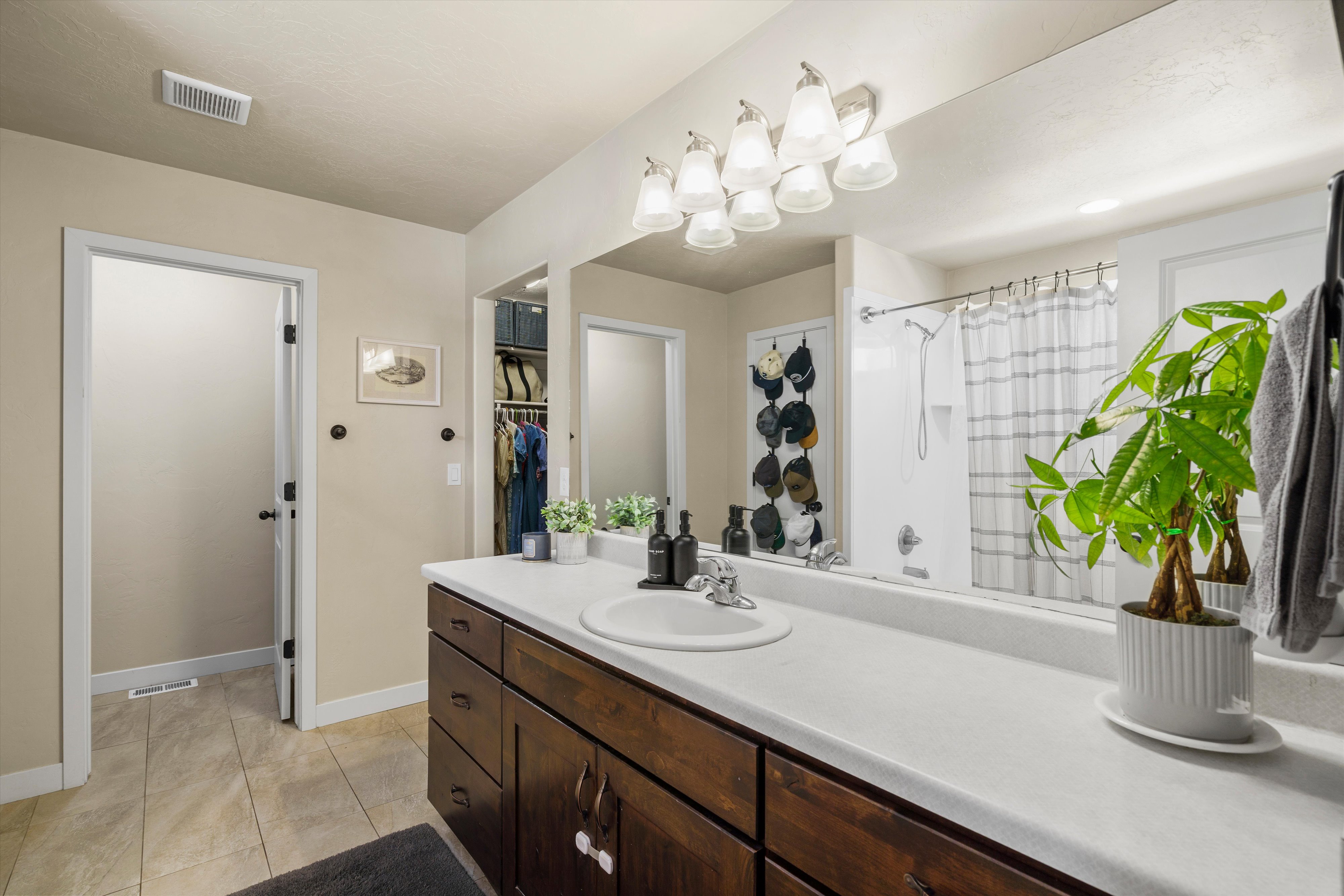 Spacious bathroom featuring an expansive vanity with wood cabinetry, a white countertop, and a single basin sink