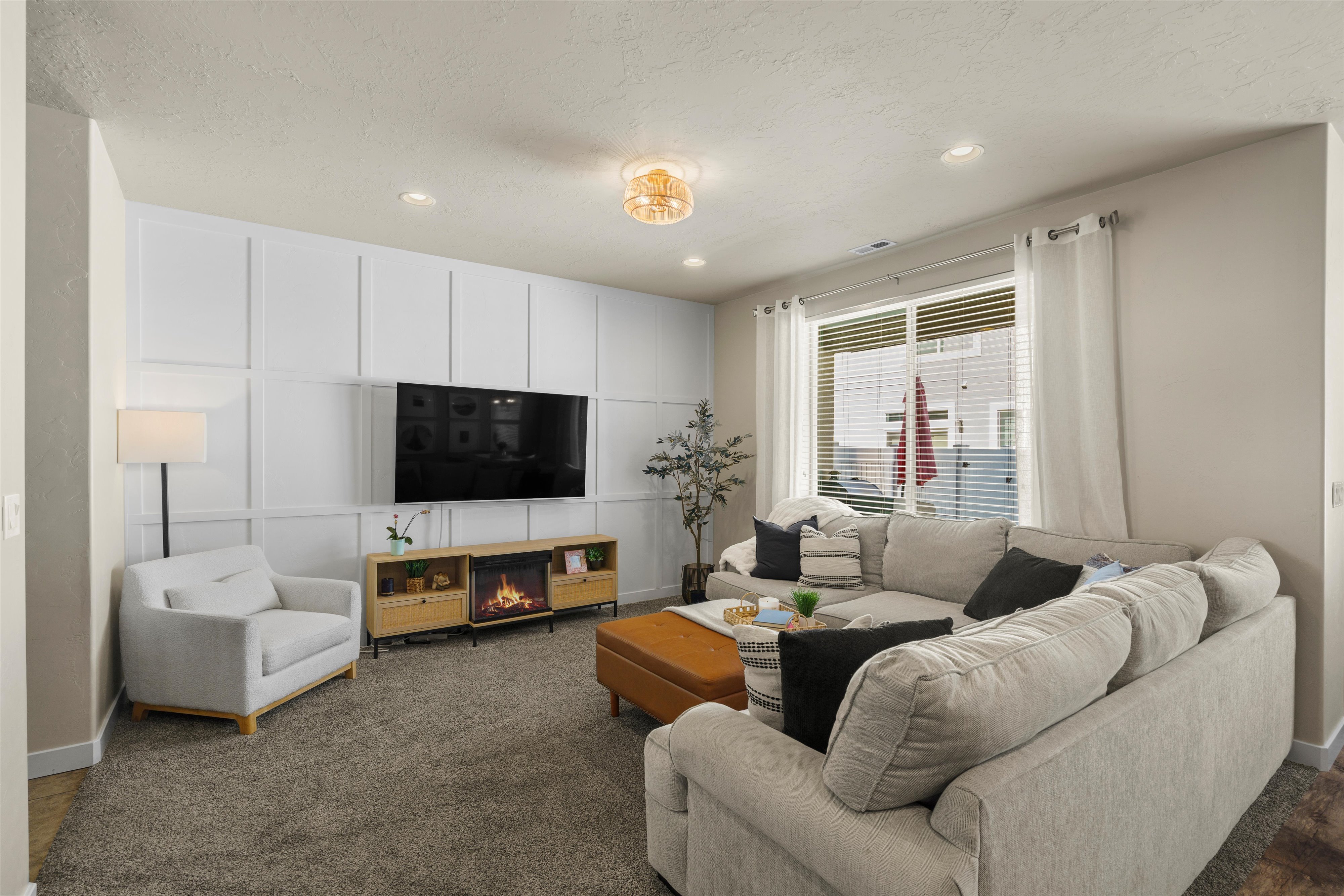 Living area featuring a detailed accent wall with paneling, recessed lighting, and a built-in media console with an integrated electric fireplace
