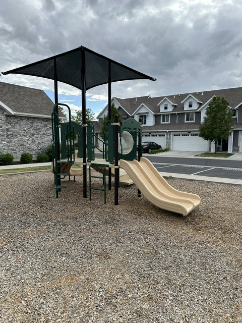 Outdoor play structure featuring a slide, climbing elements, and a protective shade canopy