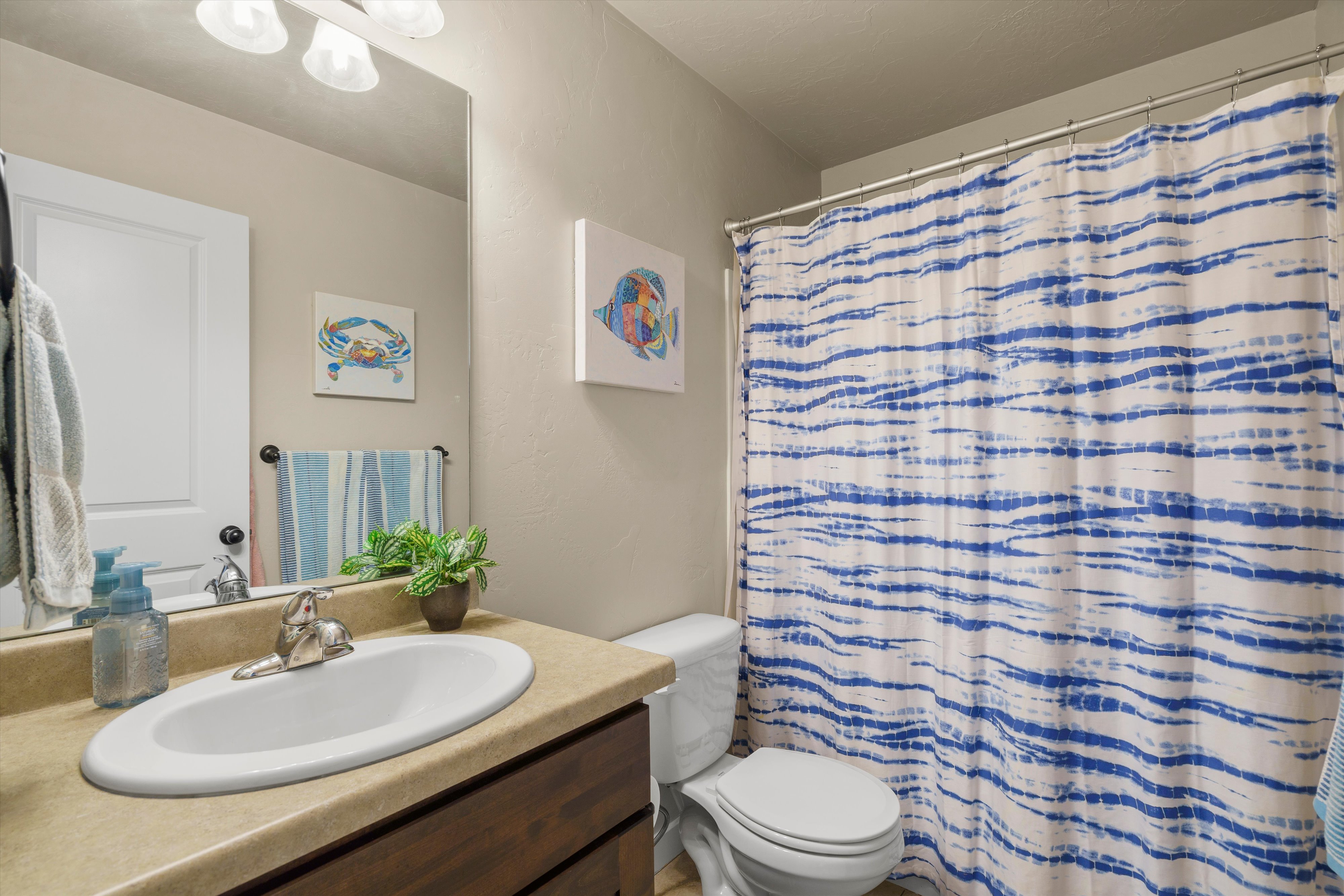 Bathroom featuring a single vanity with an integrated sink, a built-in toilet, and a shower/tub combination
