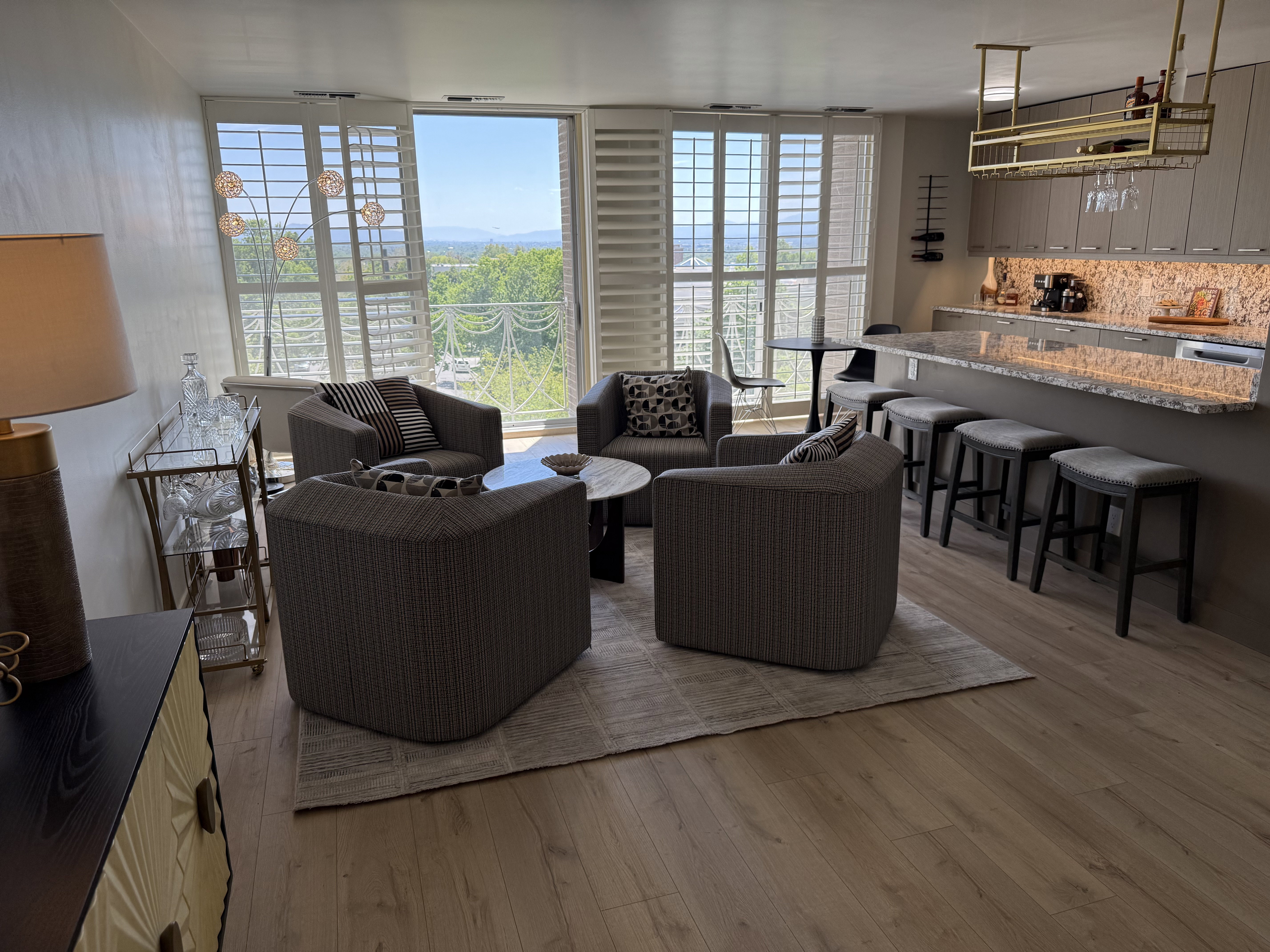 Open-concept living space featuring wood-finish flooring, a kitchen island with seating, upper and lower cabinetry, and a full-height tile backsplash