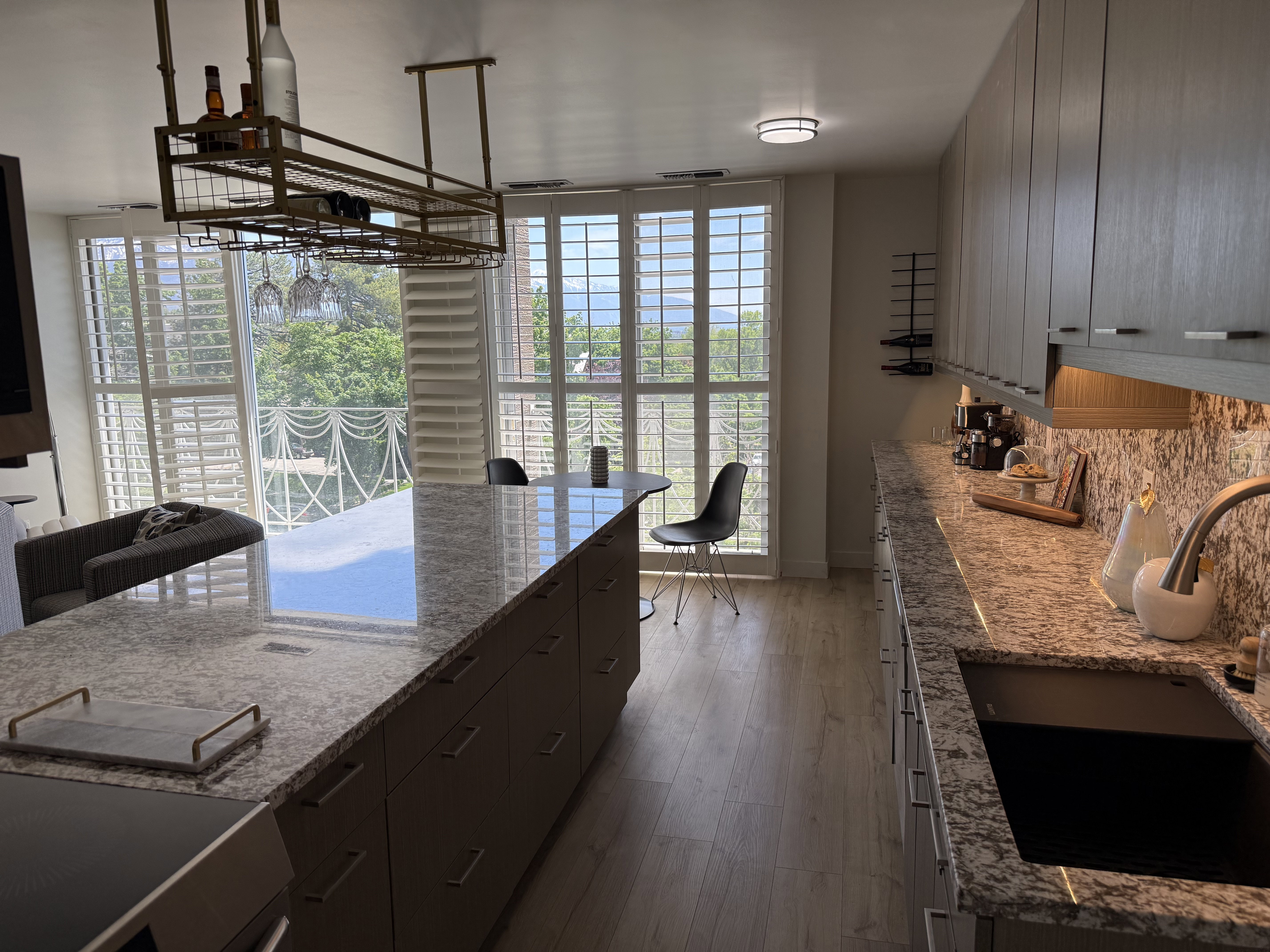 Kitchen featuring an expansive island with a polished stone countertop, a built-in cooktop, and an integrated under-mount sink