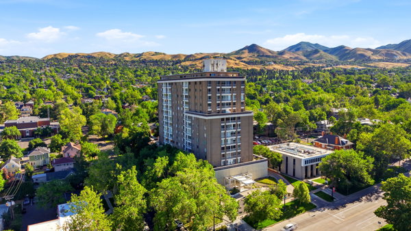 High-rise building with a tiered architectural design, set amidst a verdant landscape