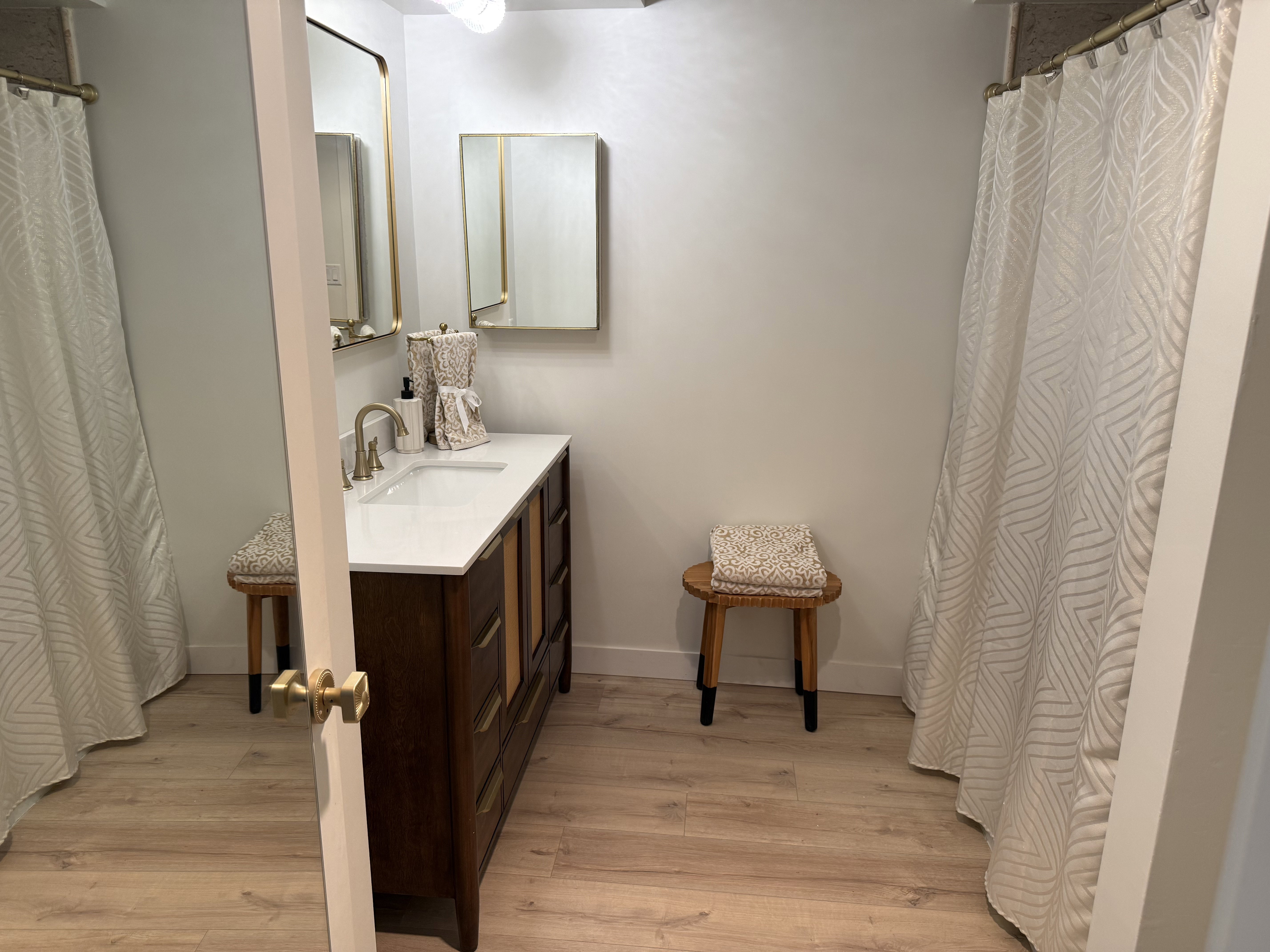 Modern bathroom featuring a long wood-finish vanity with an integrated white sink and a single-handle faucet