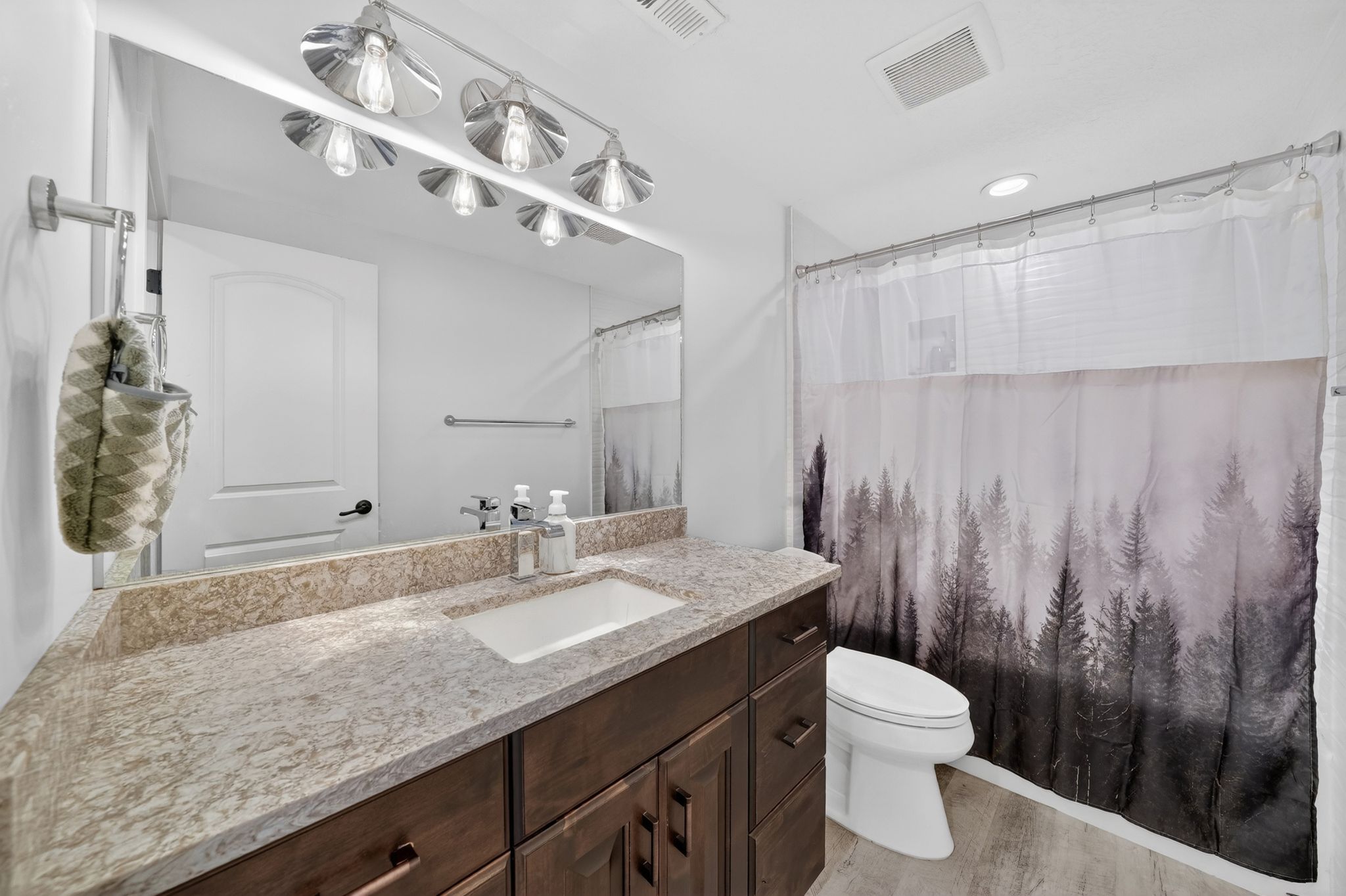 Bathroom featuring a vanity with a light-toned stone countertop, integrated rectangular sink, and dark wood-finish cabinetry