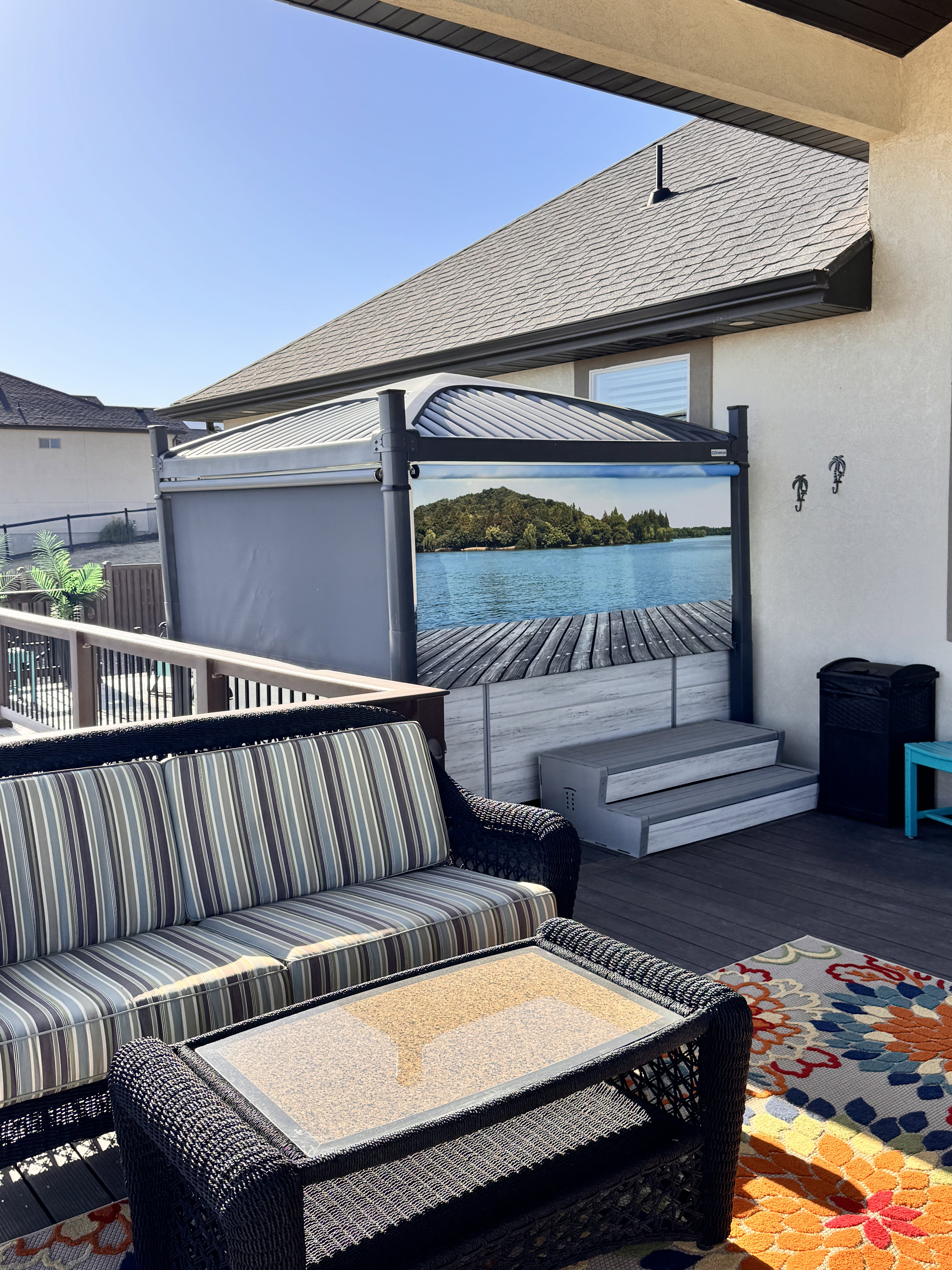 Spacious outdoor deck featuring dark composite decking, a built-in hot tub with steps, and a privacy screen