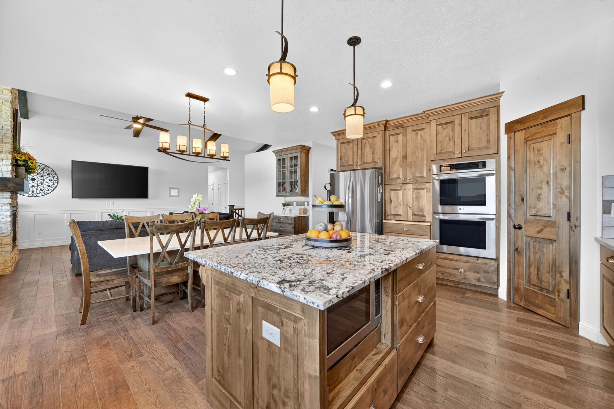 Spacious kitchen island with a granite countertop, integrated microwave, and pendant lighting