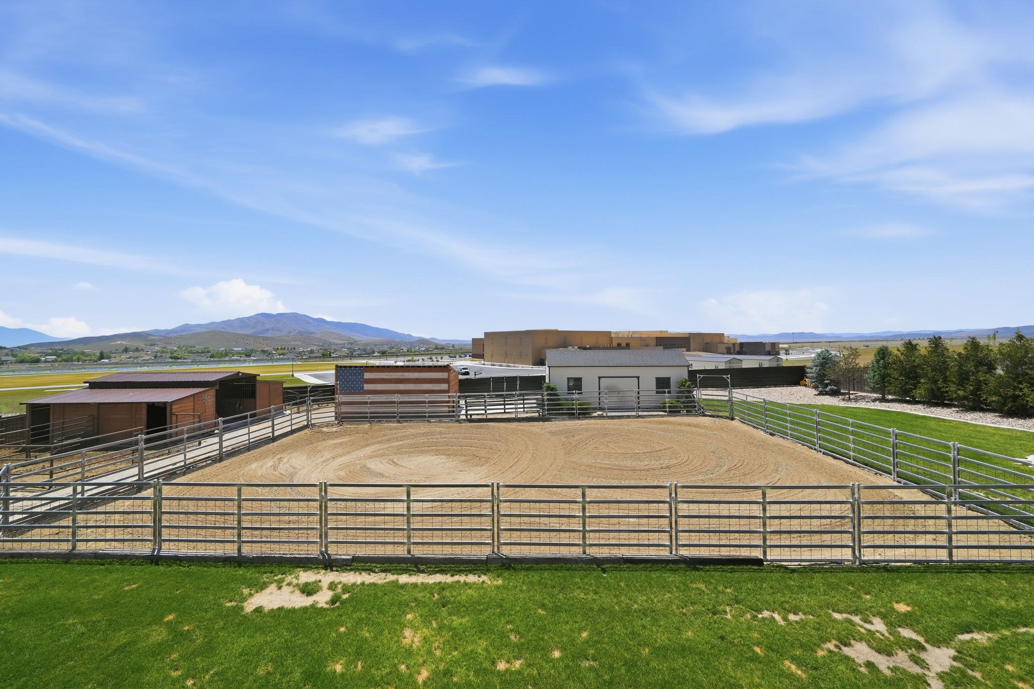 Expansive equestrian arena featuring a sand riding surface and metal fencing