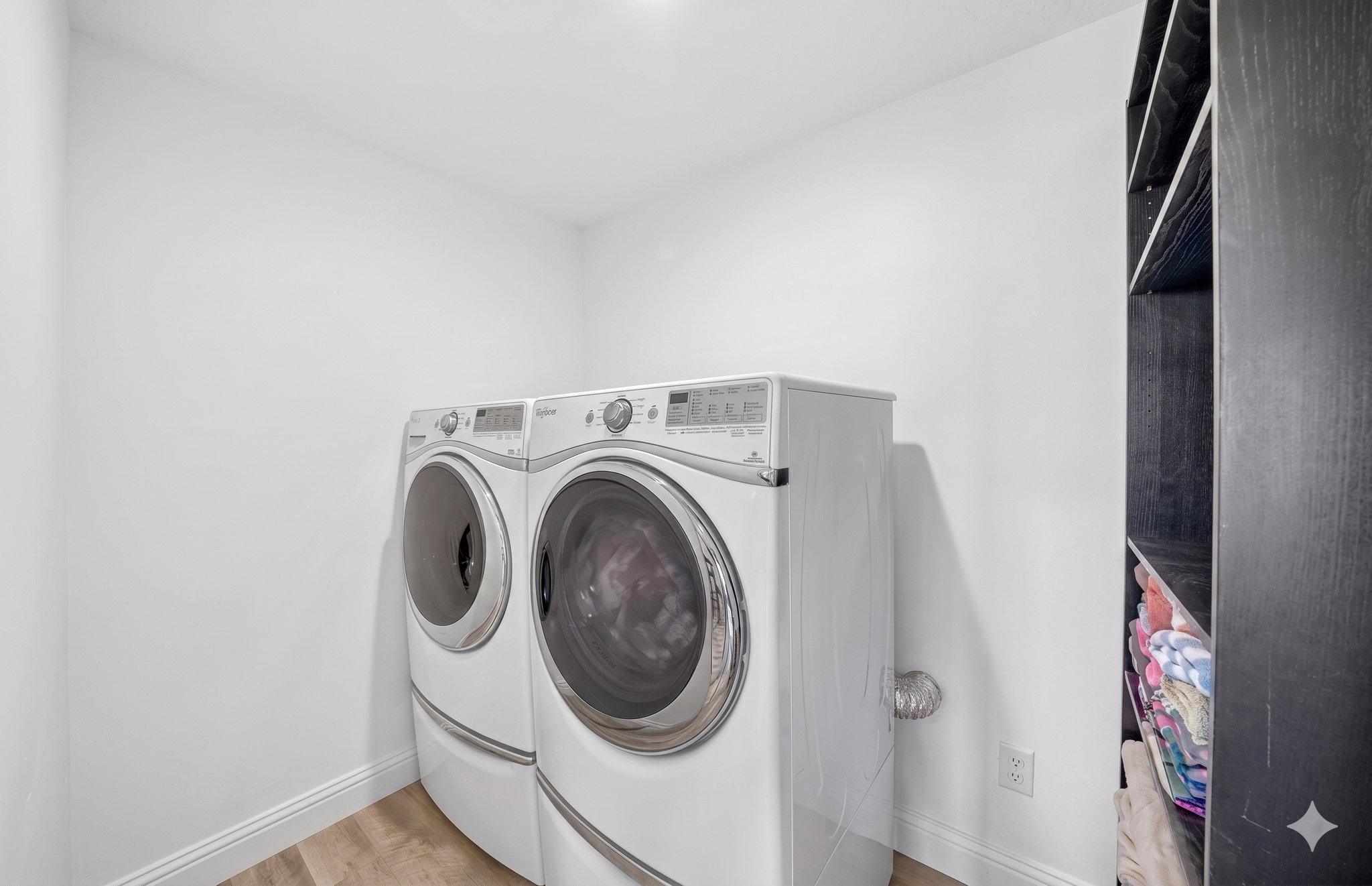 Dedicated laundry area featuring wood-finish flooring and white baseboards