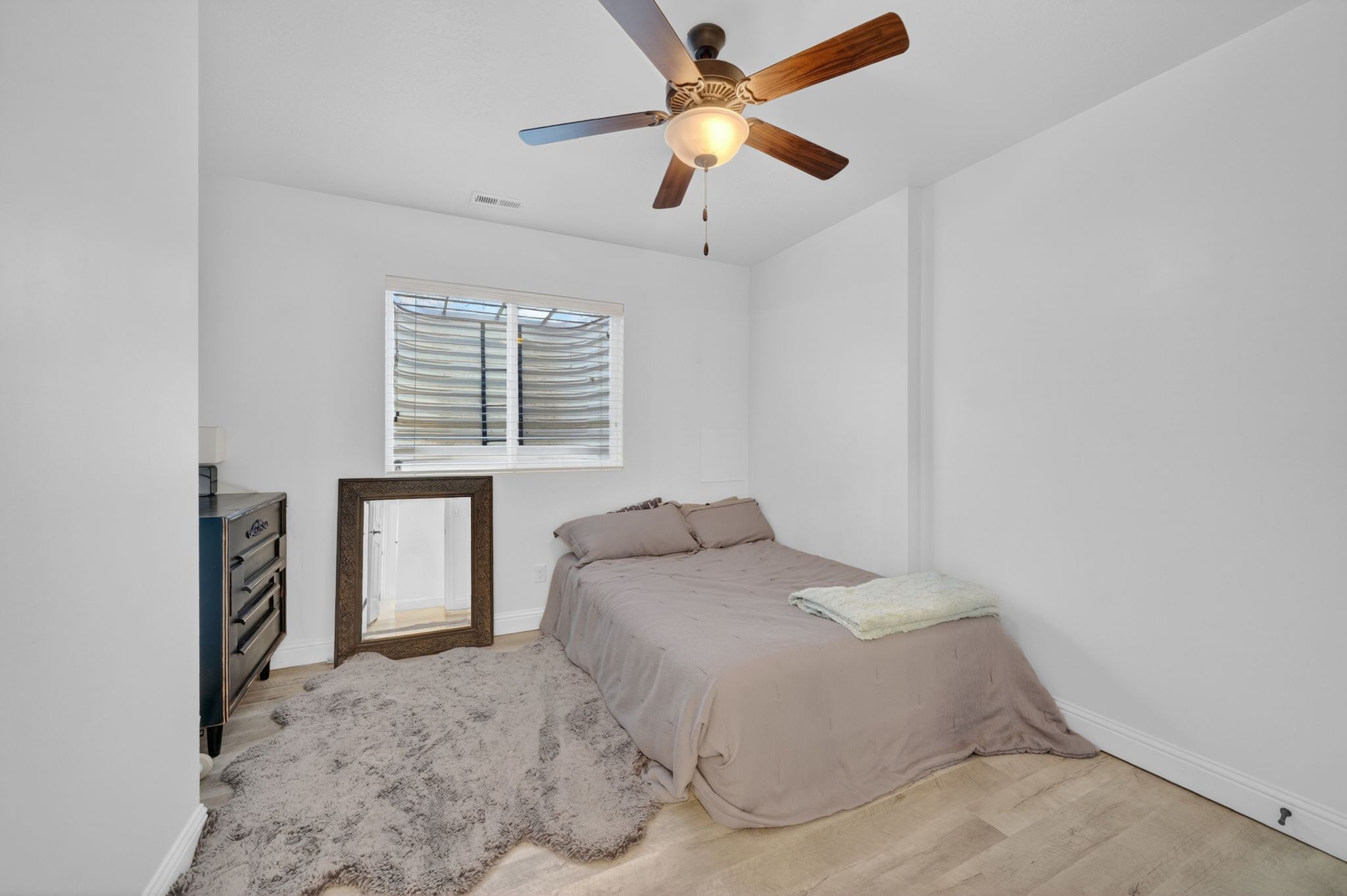 Room with light wood-finish flooring and a ceiling fan with integrated lighting