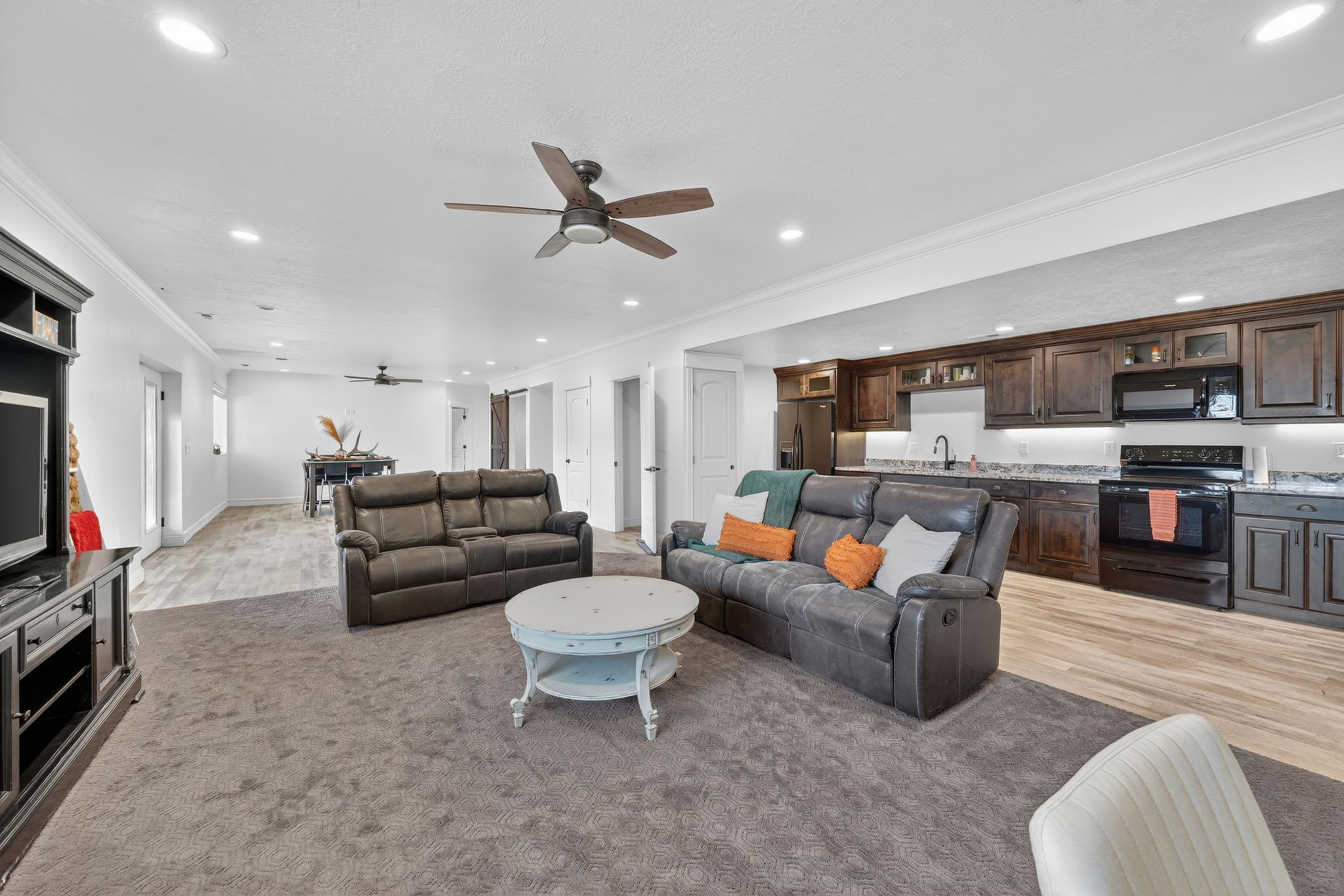 Spacious living area featuring recessed lighting, a ceiling fan, and dark wood-finish cabinetry