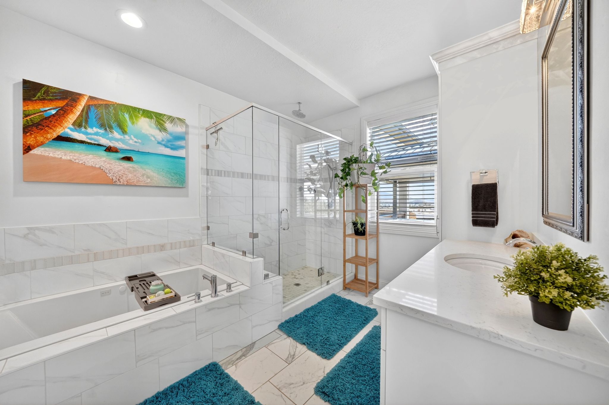 Bathroom featuring a built-in soaking tub, a glass-enclosed shower, a single vanity with a white countertop and integrated sink, white tiled walls, and a window with horizontal blinds