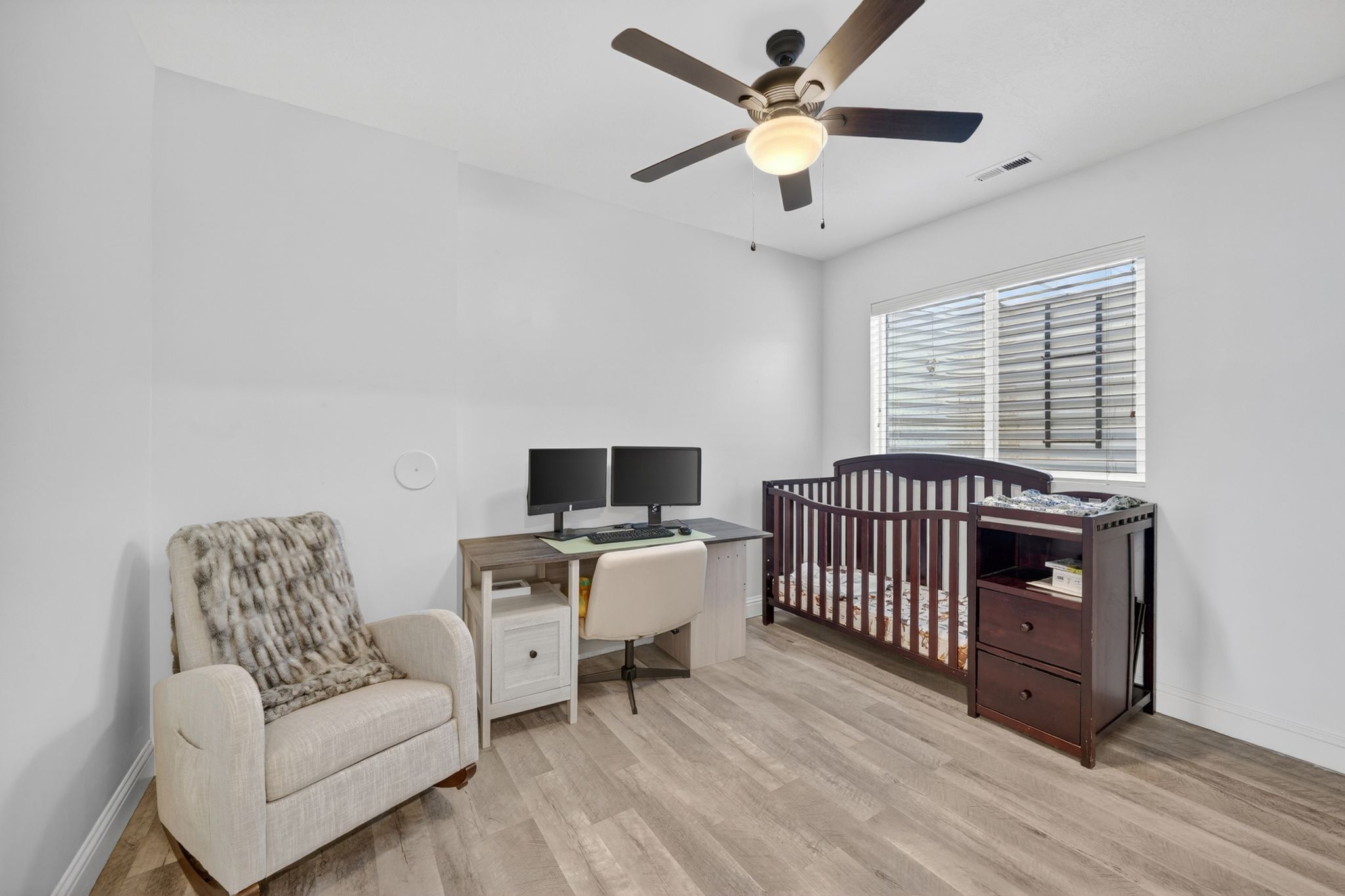 Room featuring wood-finish flooring, a ceiling fan with integrated lighting, and a window with horizontal blinds