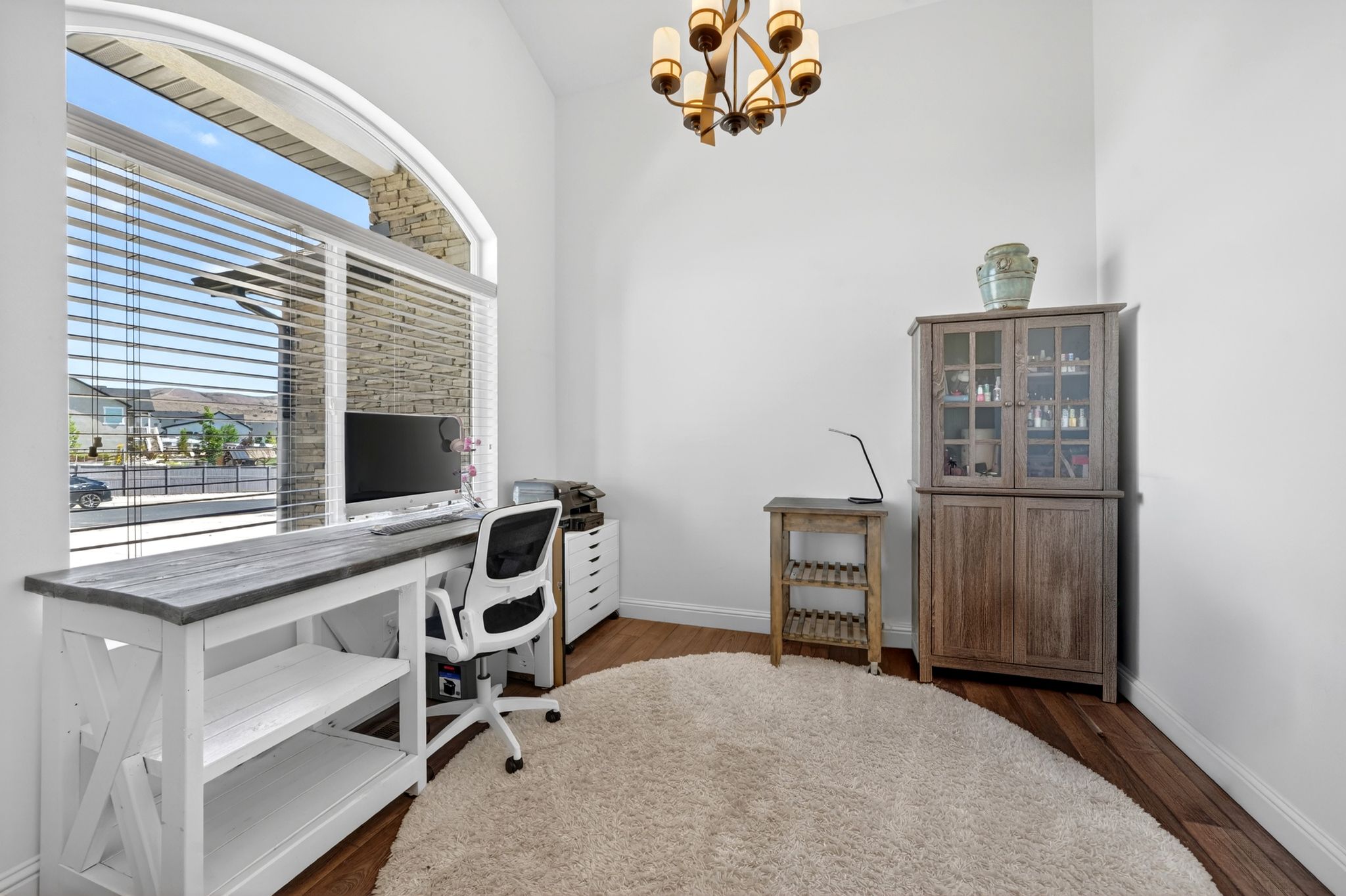 Vaulted ceiling interior space with an arched window featuring horizontal blinds