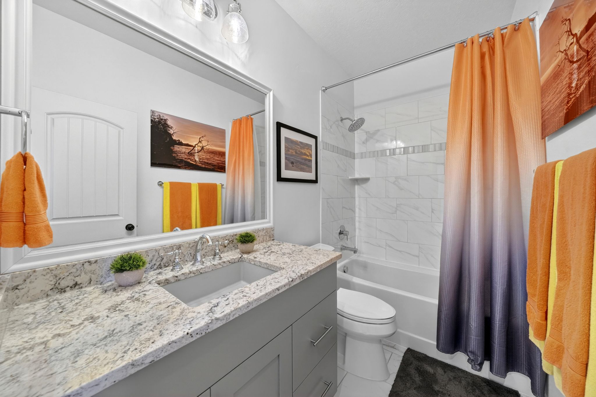 Bathroom featuring a gray vanity with a light-toned patterned countertop, an undermount sink, and a framed mirror