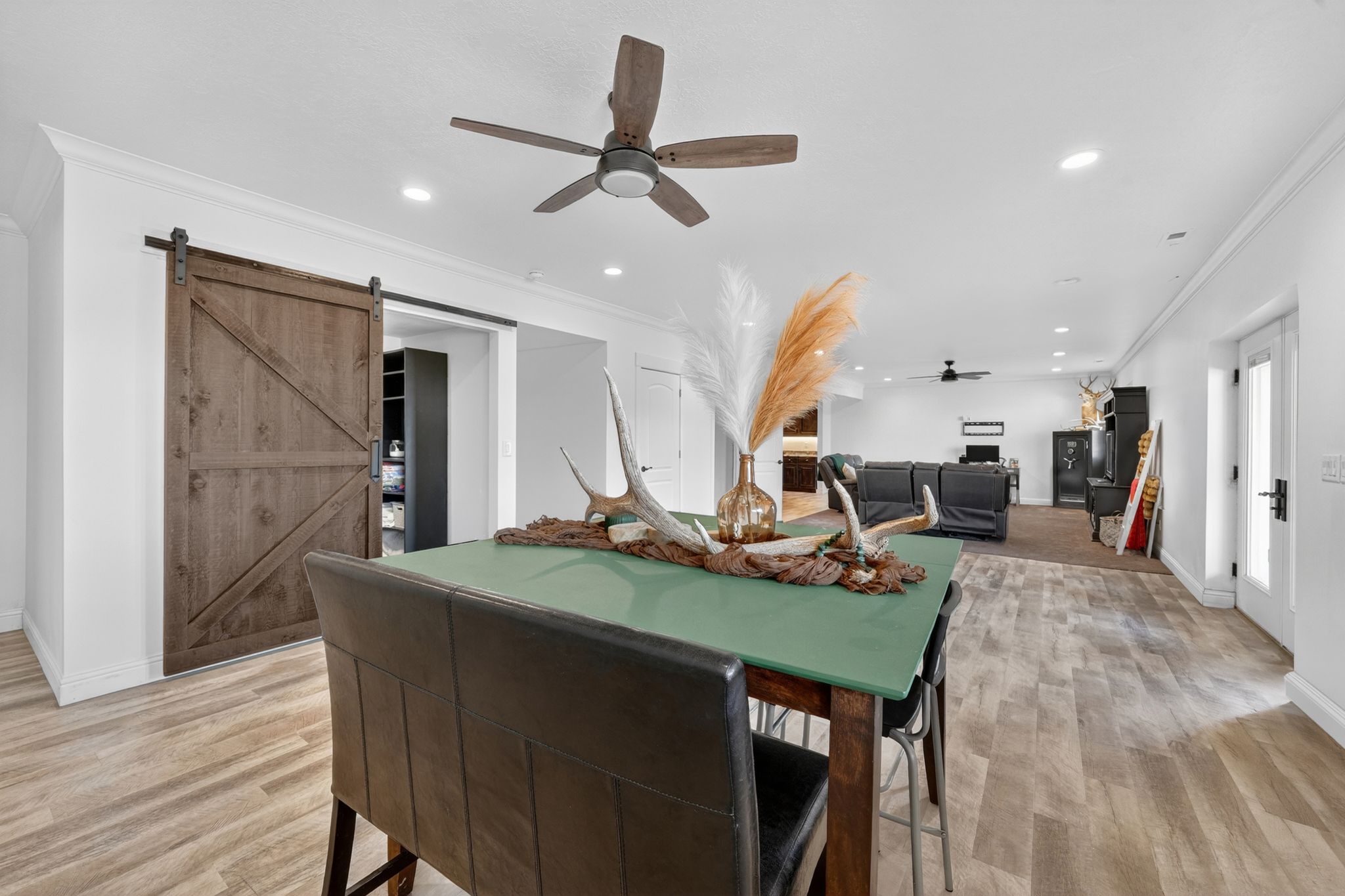 Spacious interior featuring a rustic barn door, recessed lighting, crown molding, wood-finish flooring, and a ceiling fan