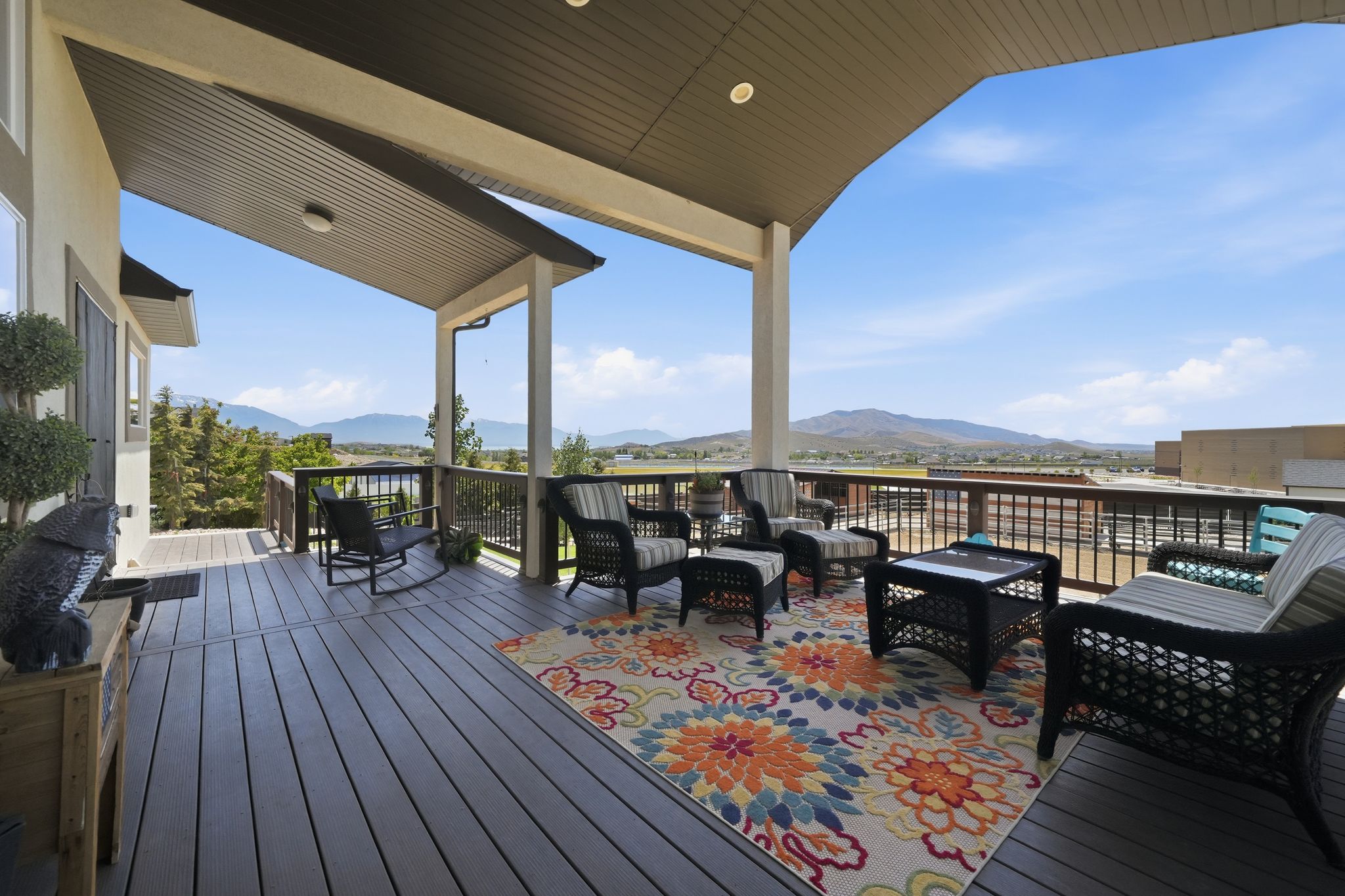 Spacious covered deck featuring composite decking, recessed lighting, and a panoramic mountain backdrop