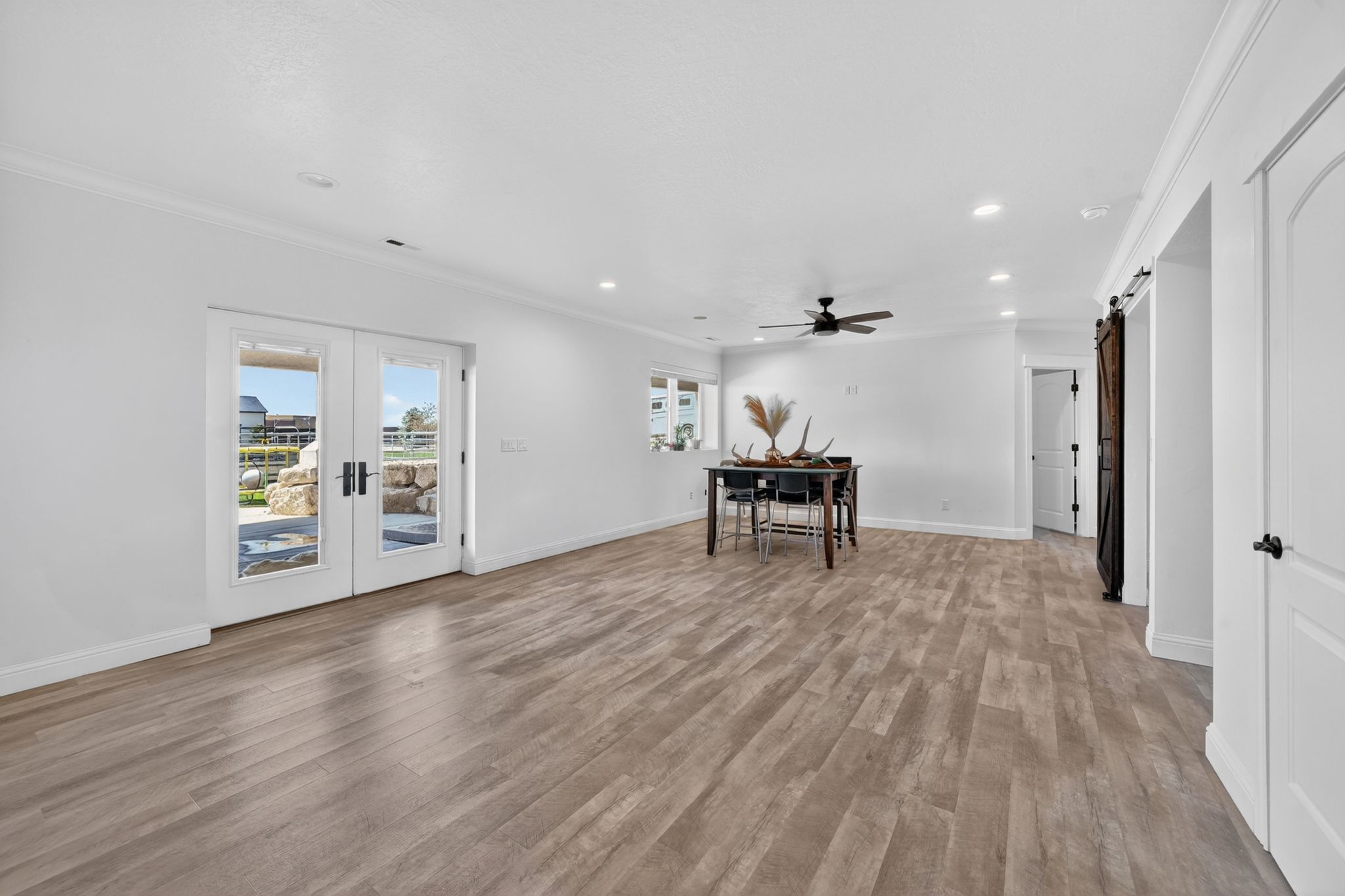 Spacious interior featuring wood-finish flooring, white walls, and French doors leading to an exterior area
