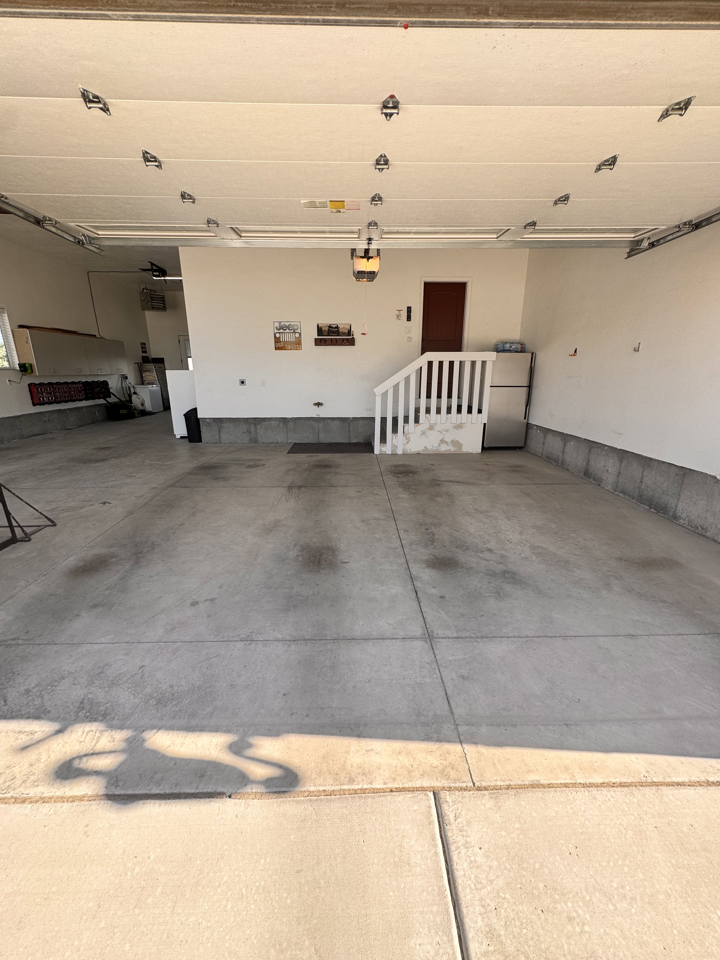 Spacious garage featuring concrete flooring, an overhead garage door, built-in shelving, and an interior access door
