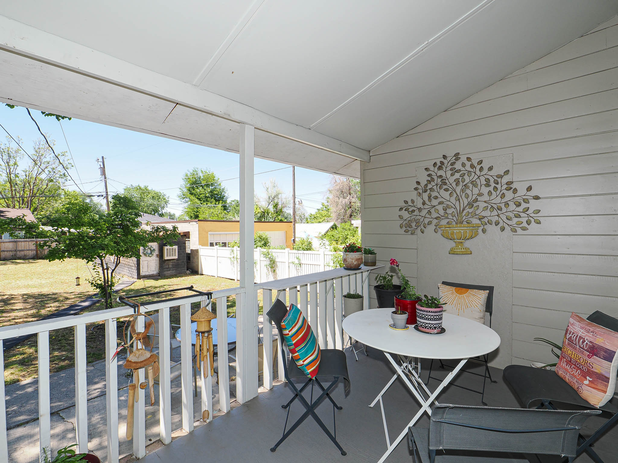 Covered porch with a pitched roof, white baluster railing, and grey flooring