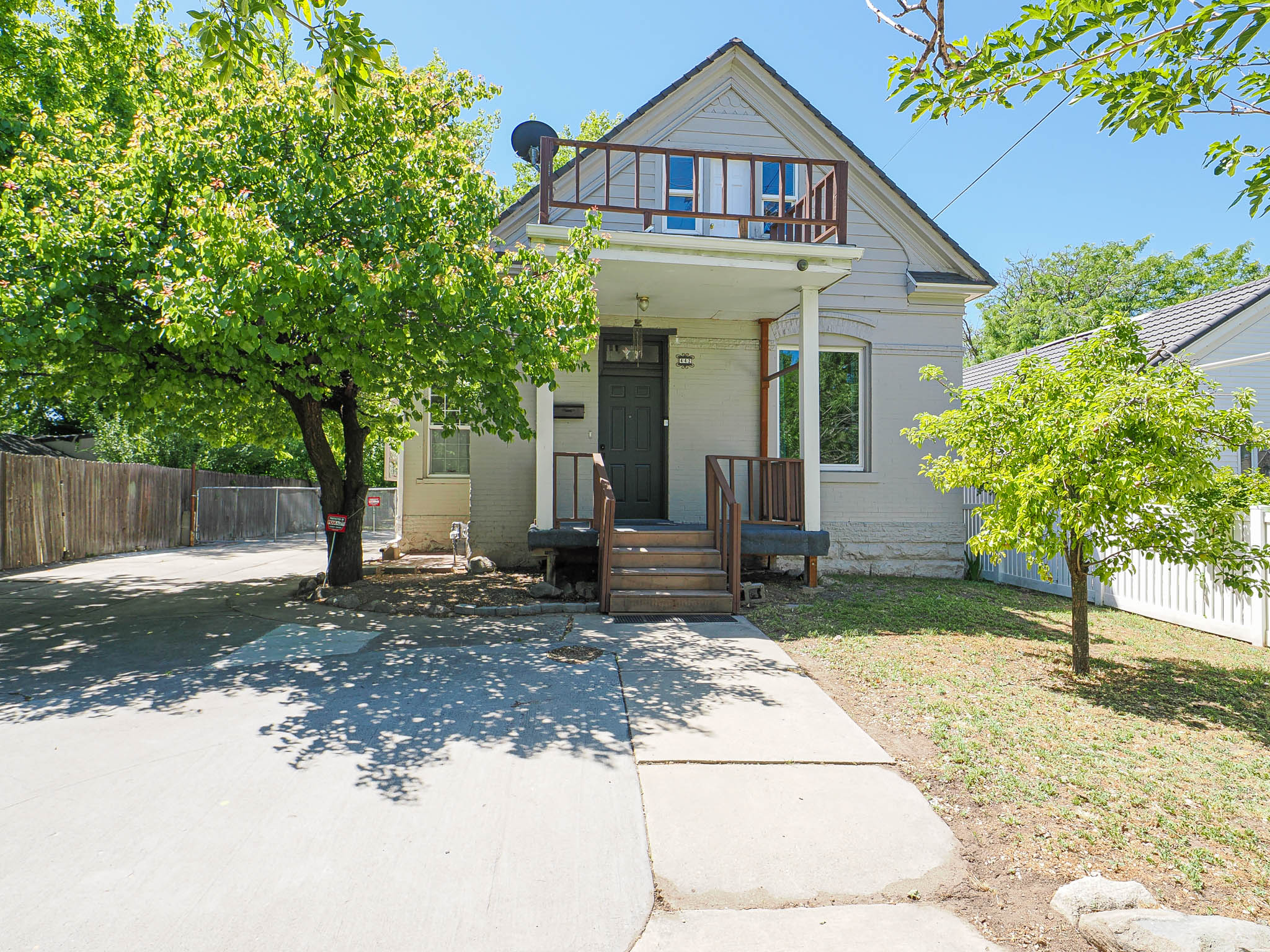 Traditional-style home exterior featuring a second-story balcony with wood railing, covered front porch, and a concrete driveway