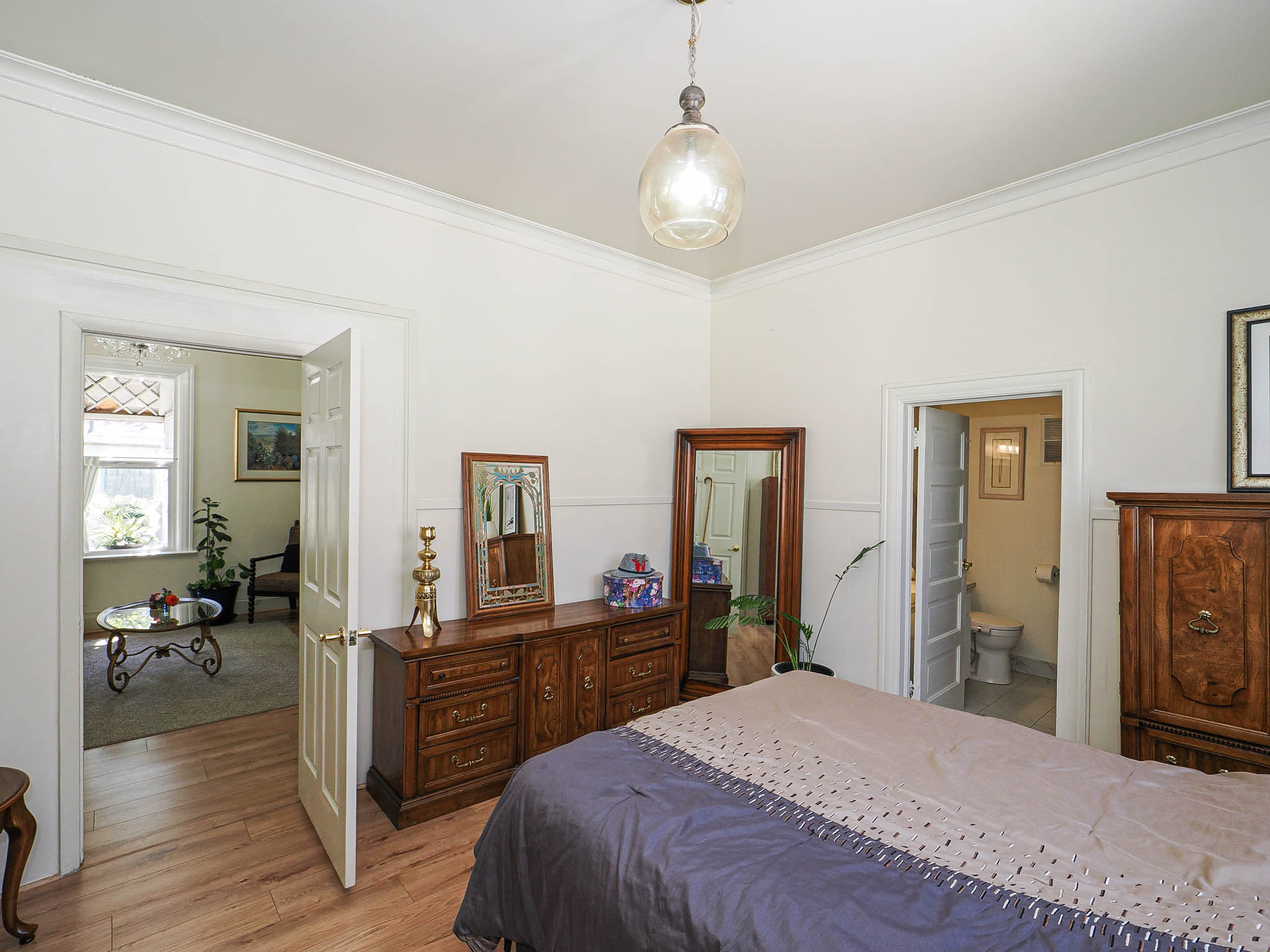 Bedroom with wood-finish flooring, crown molding, and a light-toned wall finish