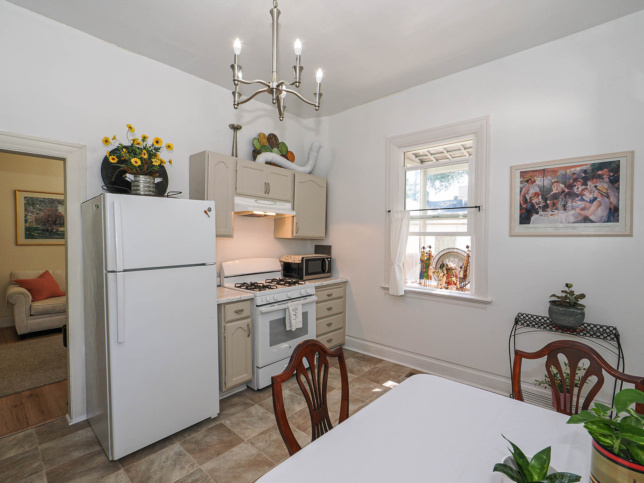 Kitchen featuring white appliances, upper and lower cabinetry, and a window with natural light